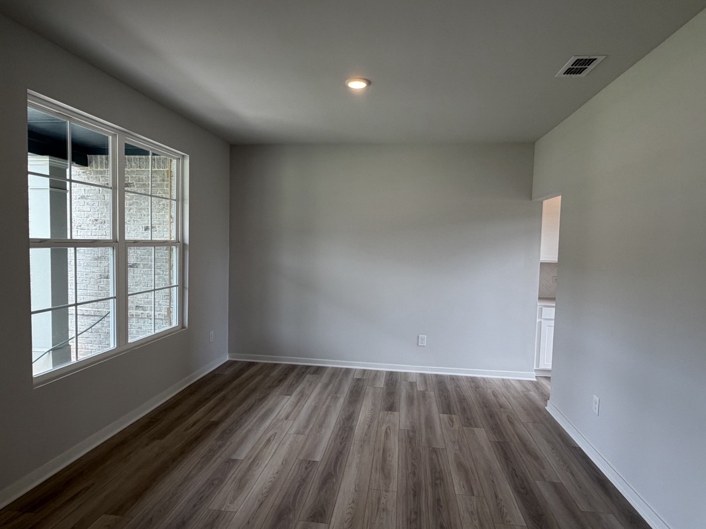 A room with a wood floor and windows.