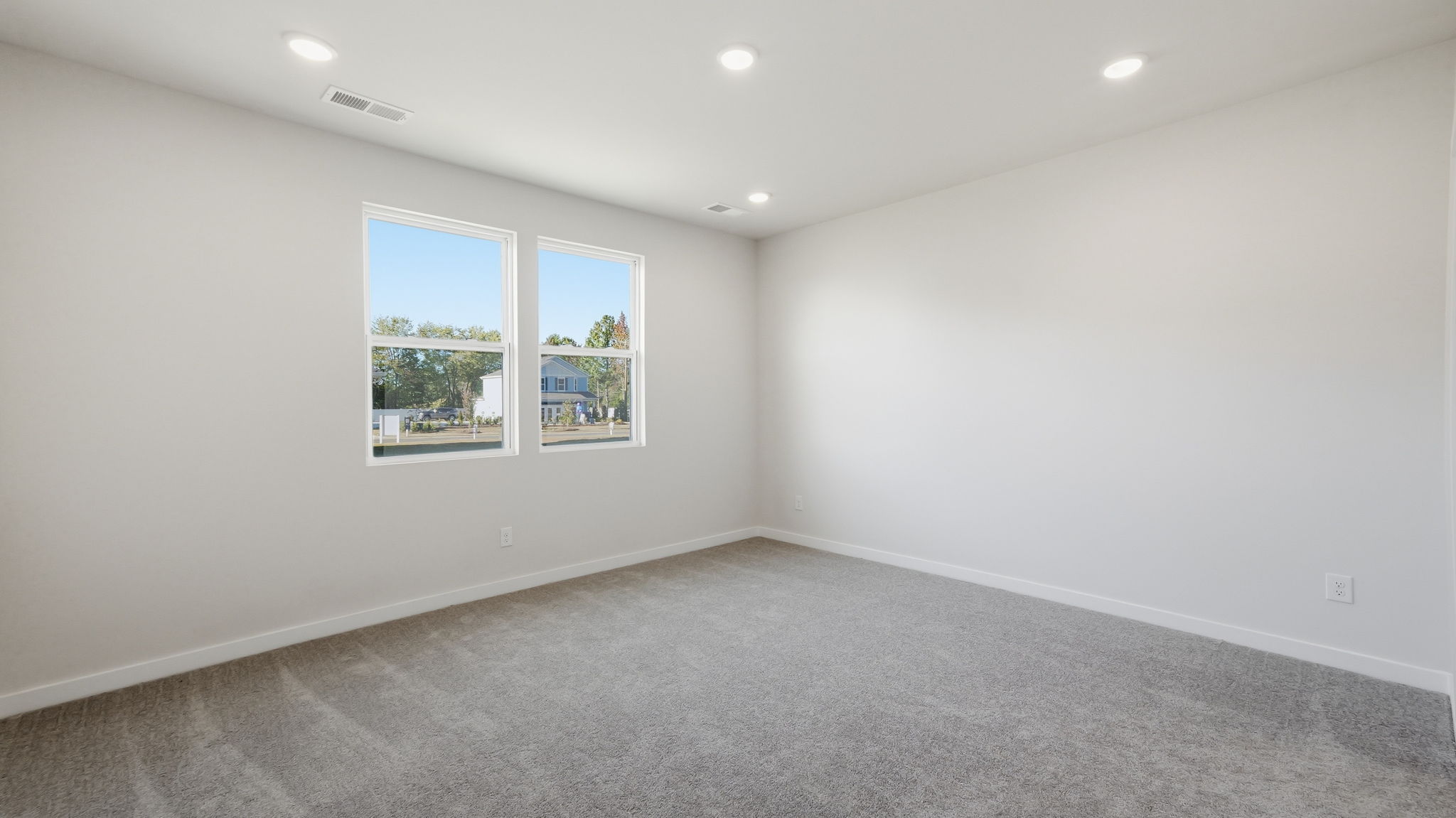 A room with a window and a white wall with a painting on it.