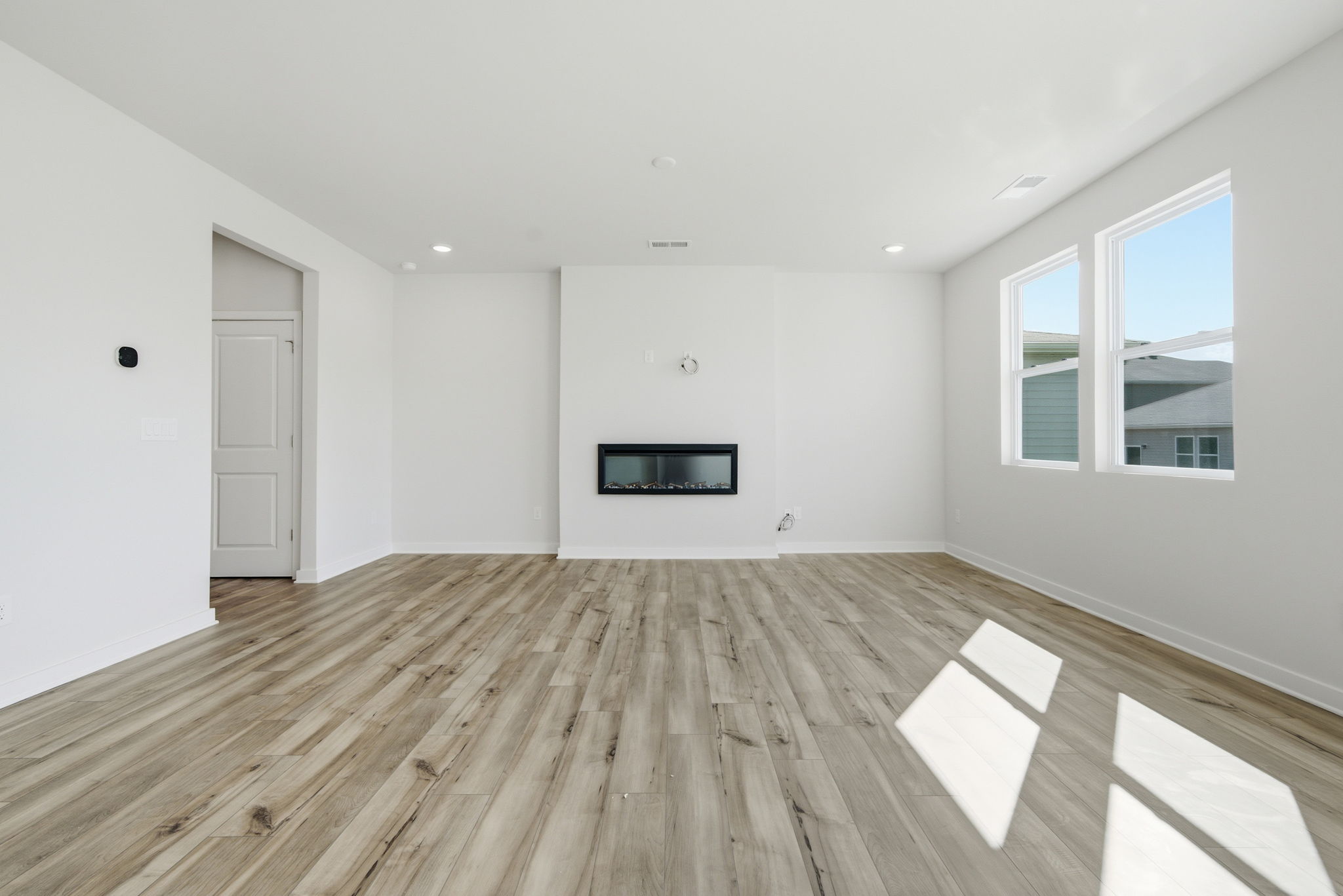 A room with a wood floor and a television on the wall.