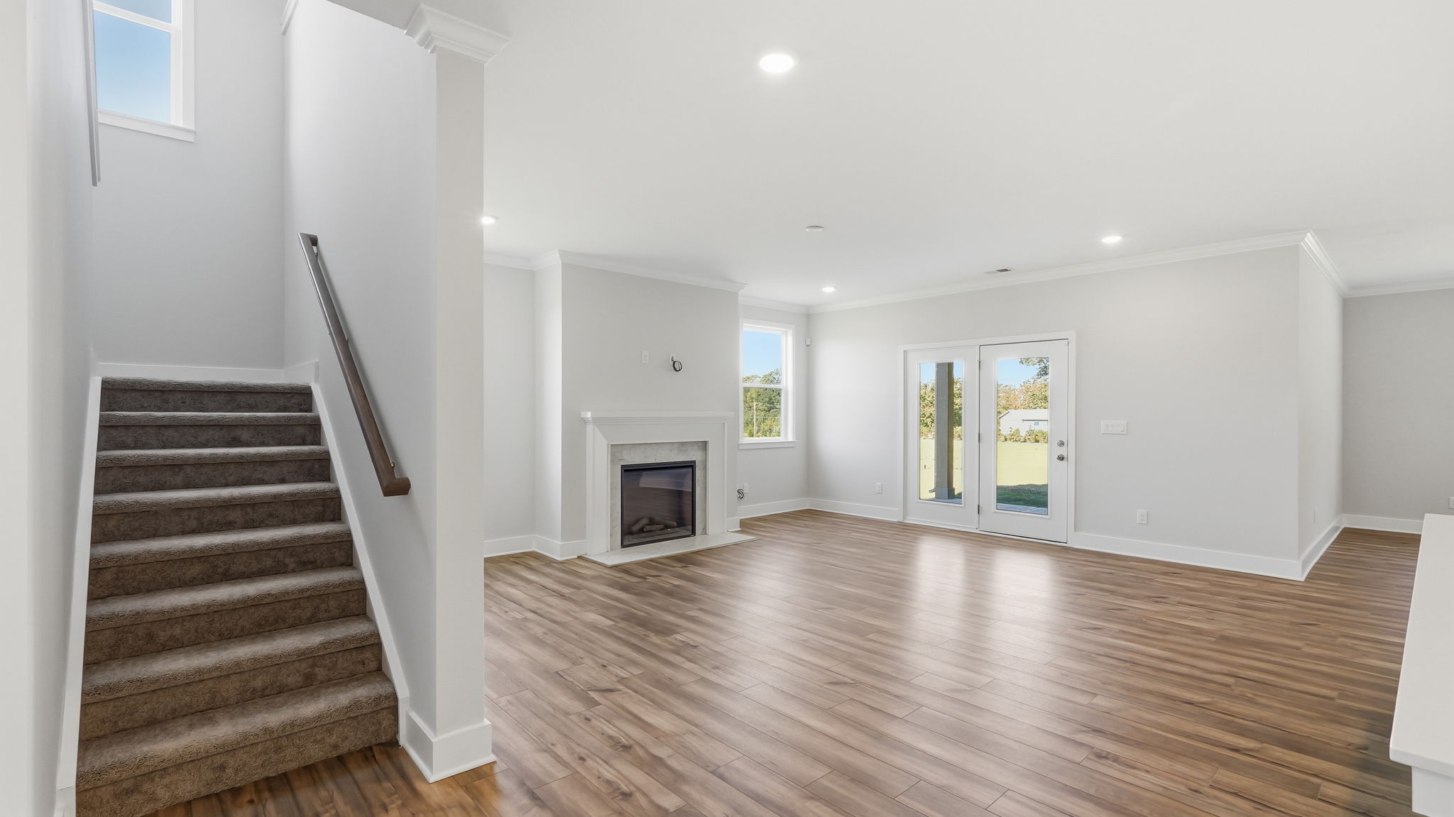 A large white room with a wood floor and a fireplace.