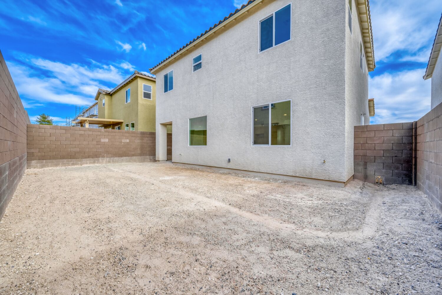 A white building with a dirt road.