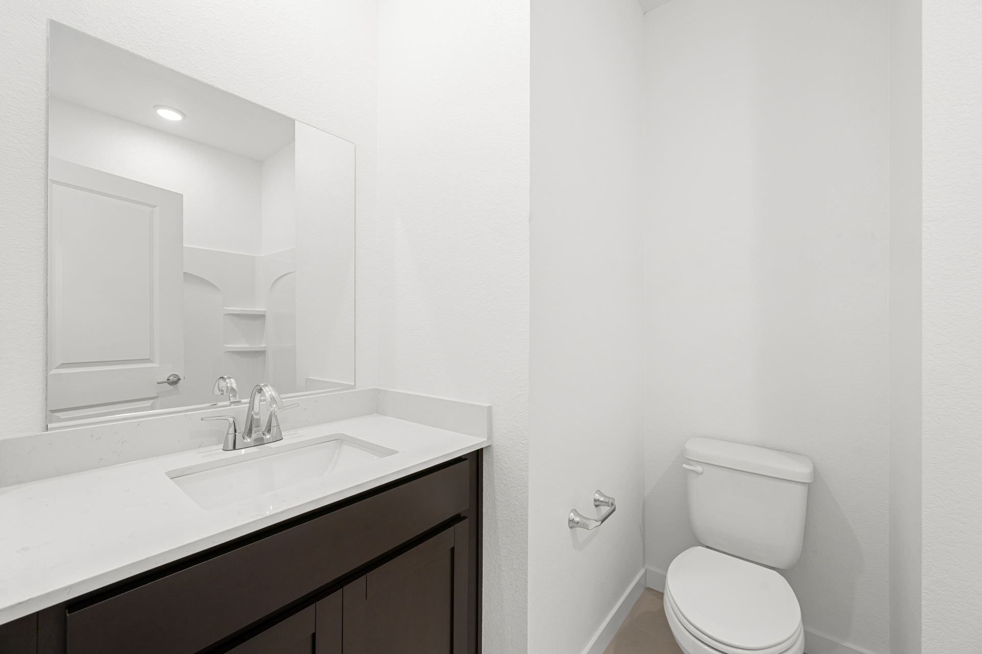 A bathroom with a sink toilet and mirror.