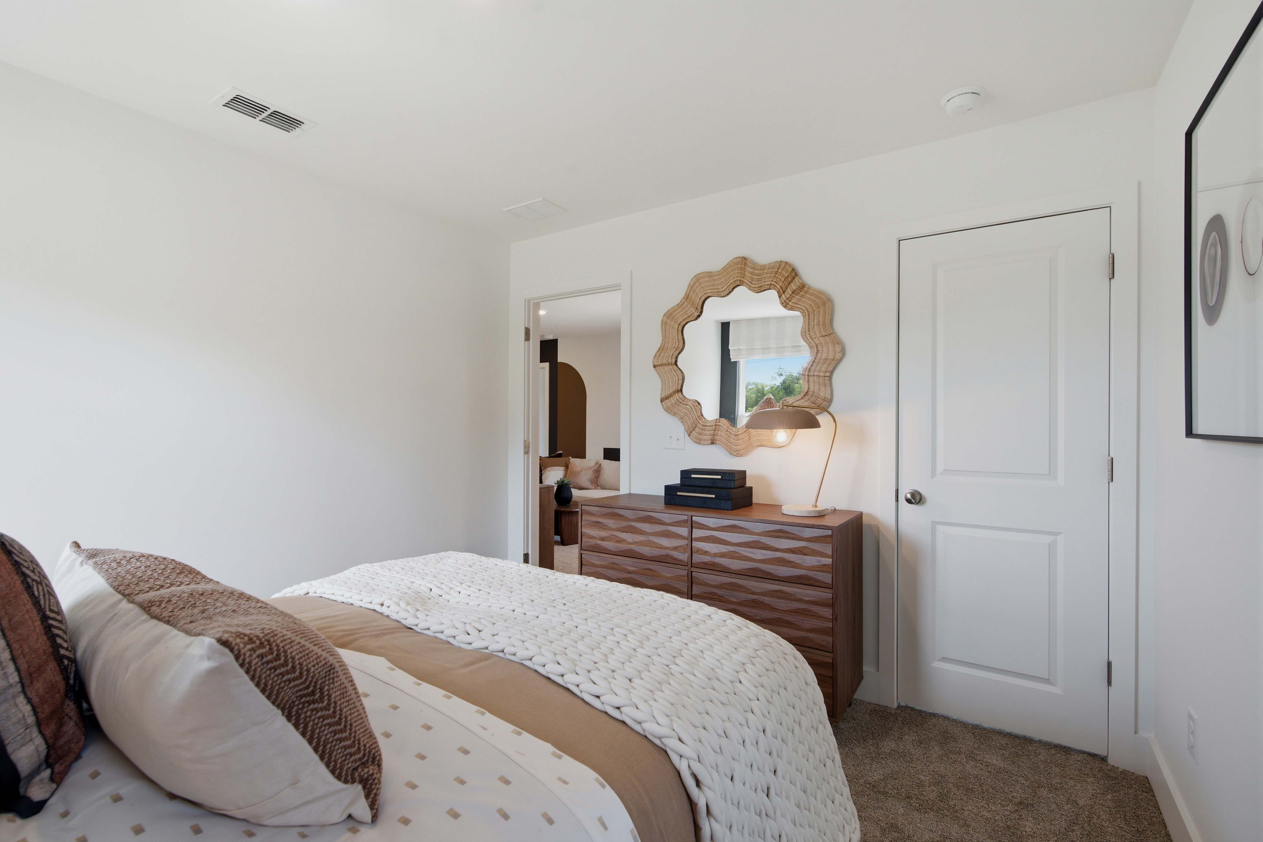 A bedroom with a mirror and a bed.