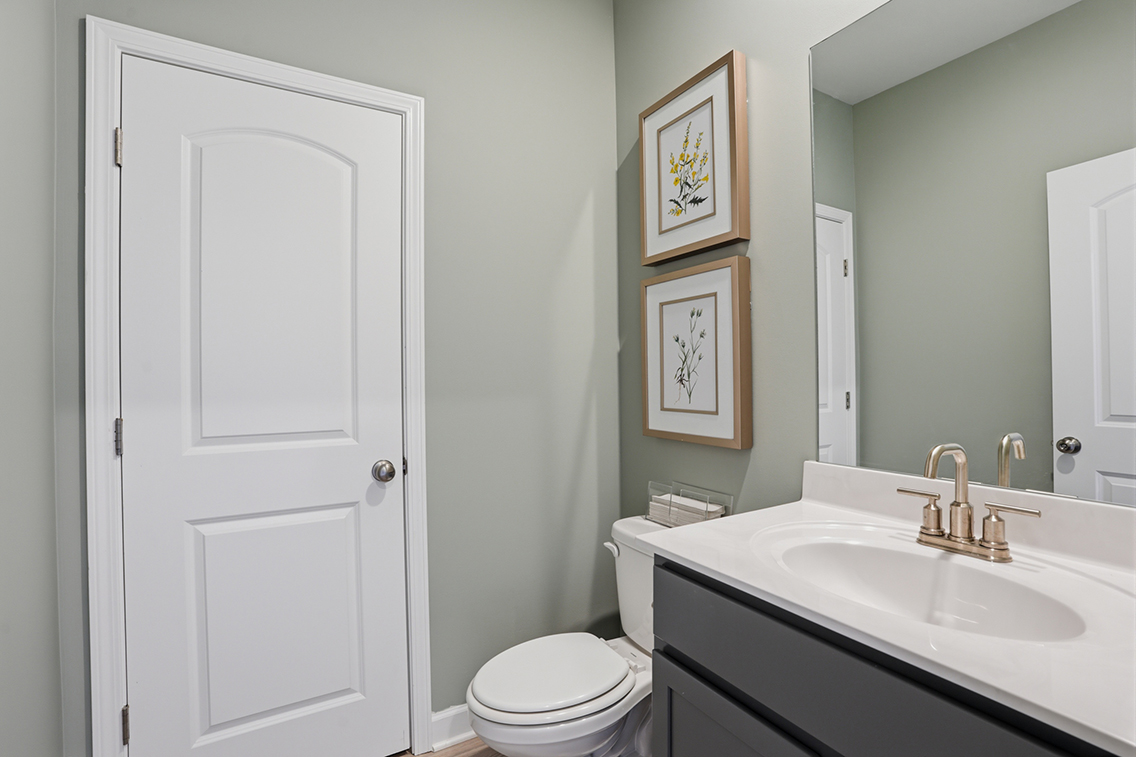 A bathroom with a sink toilet and a mirror.