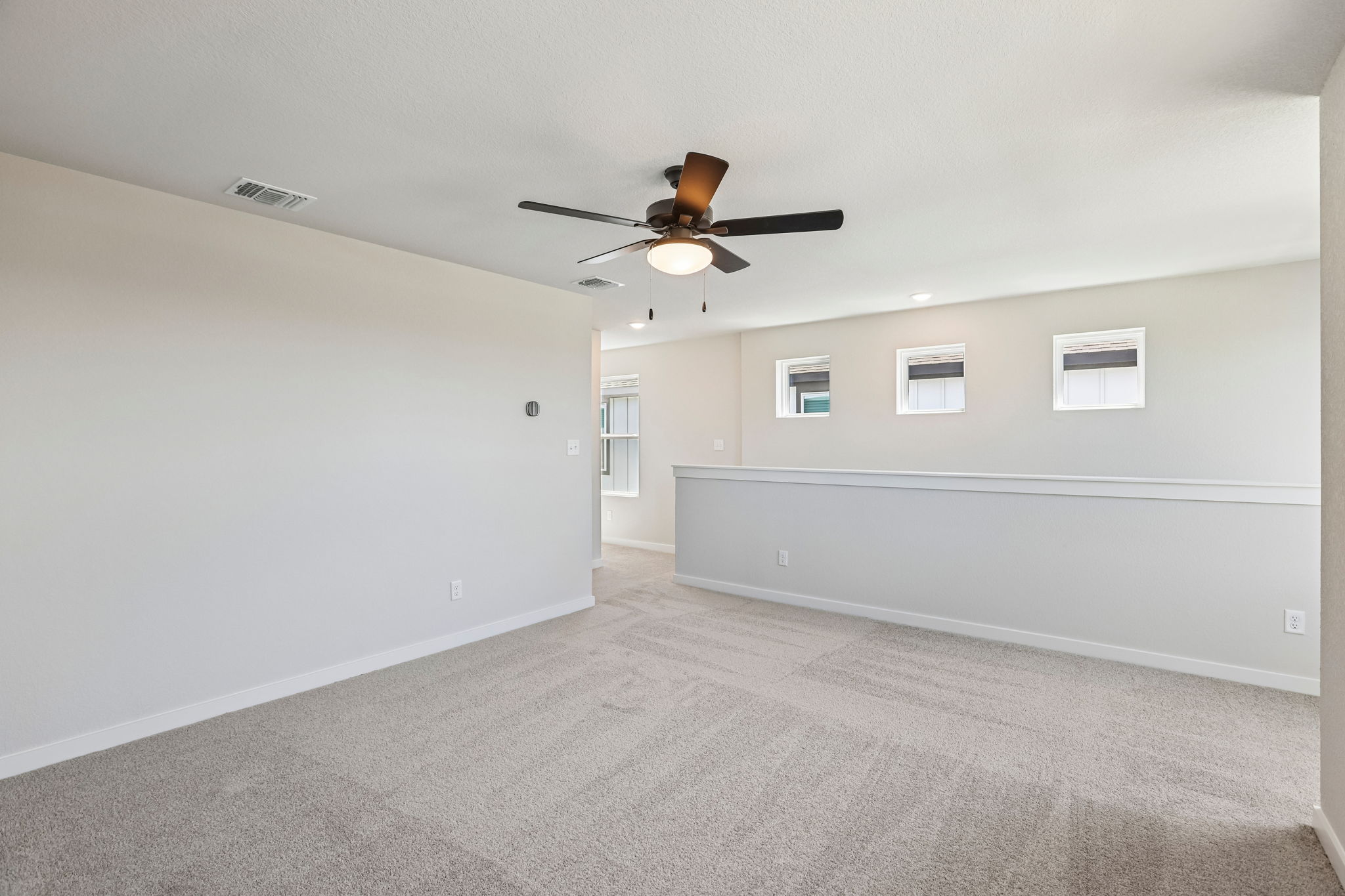 A room with a ceiling fan and a wall with a light.