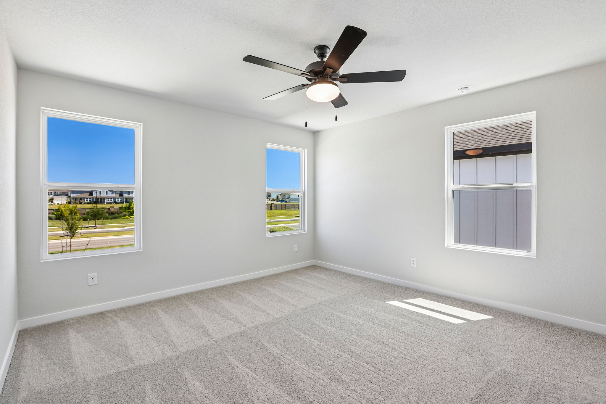 A room with a ceiling fan and a window with a view of the city.