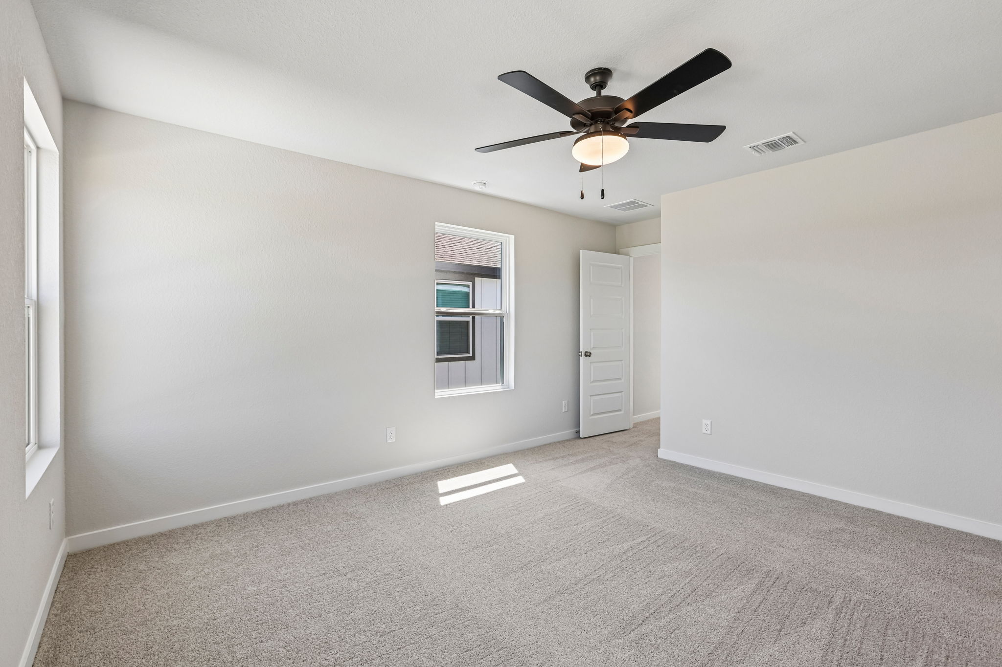 A room with a ceiling fan and a door.