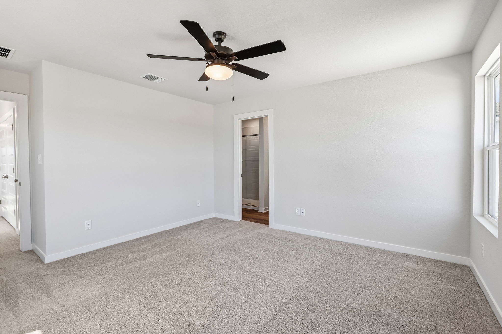 A room with a ceiling fan and a door.
