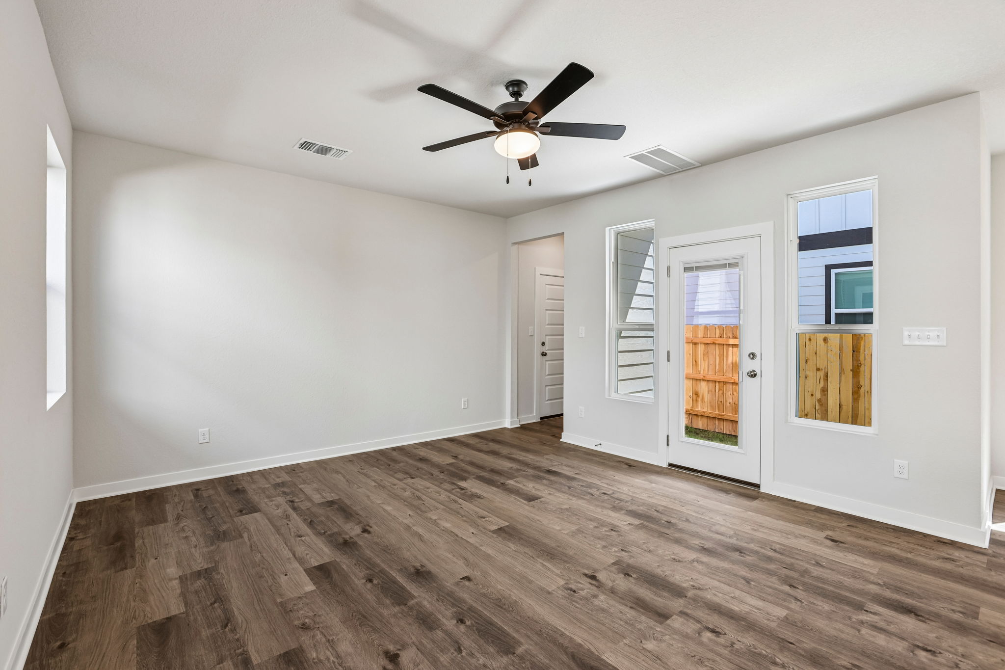 A room with a wood floor and a ceiling fan.