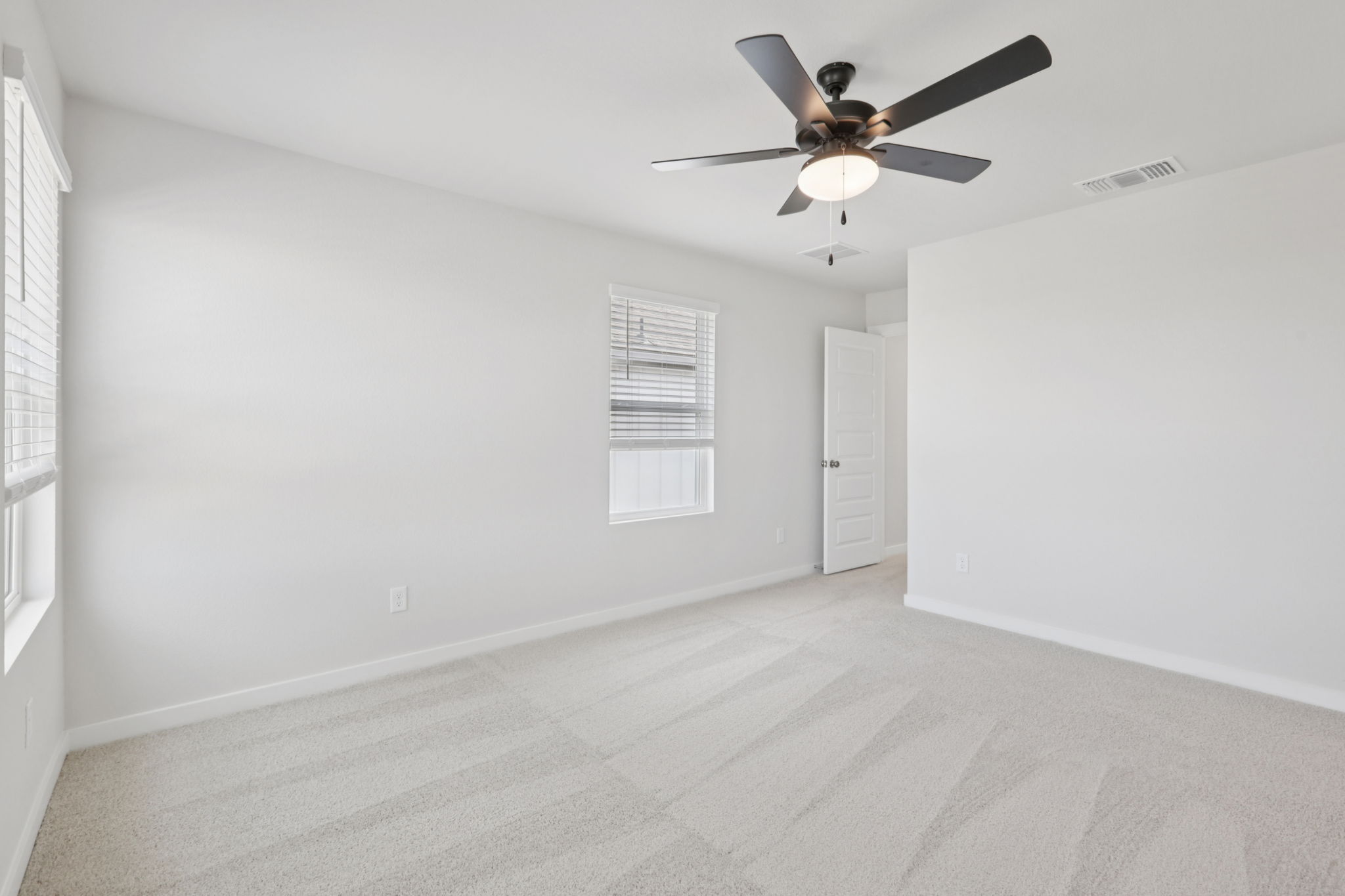 A room with a ceiling fan and a door.