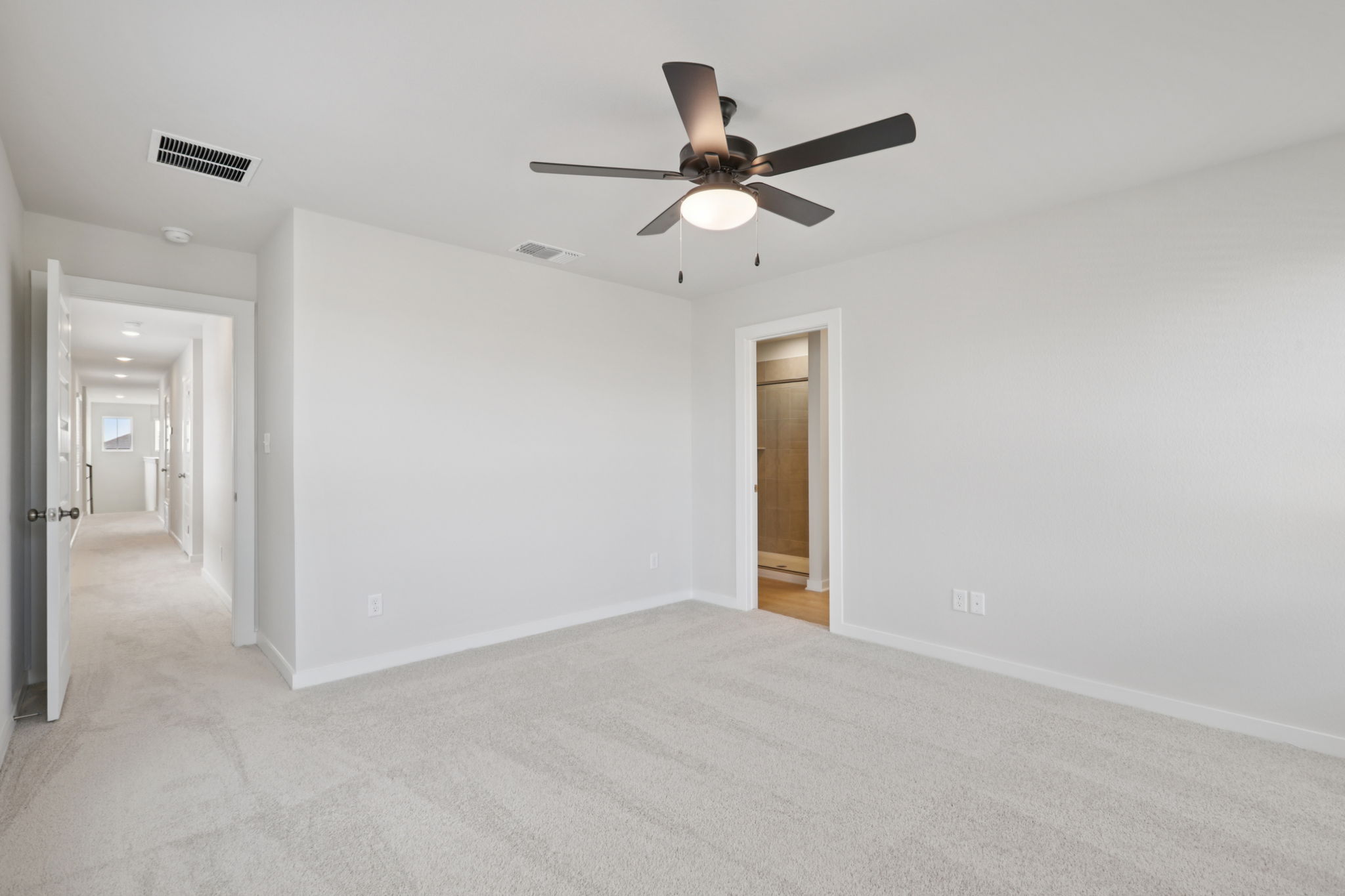 A room with a ceiling fan and a door.