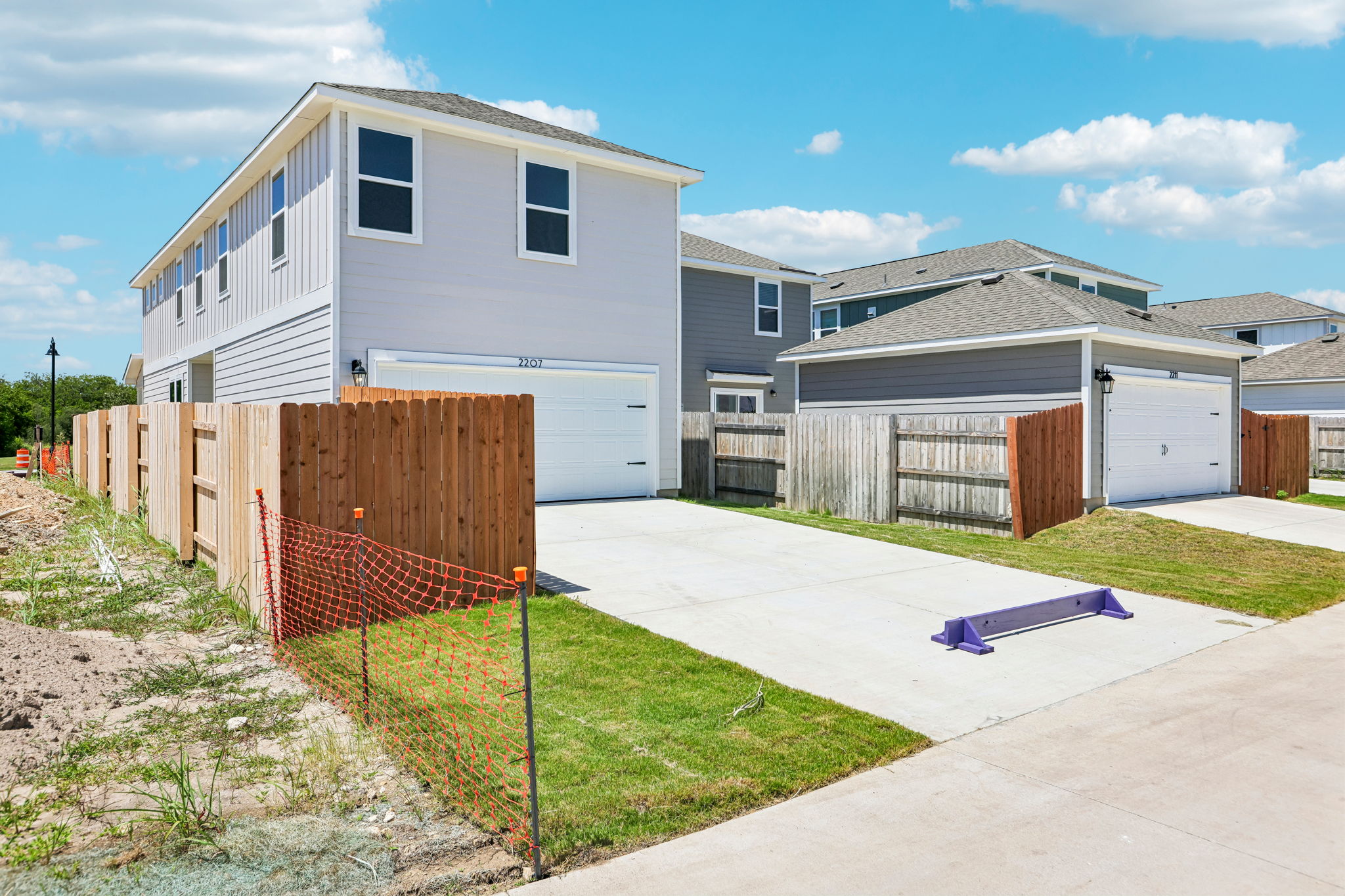 A house with a fence and a yard with a red gate.