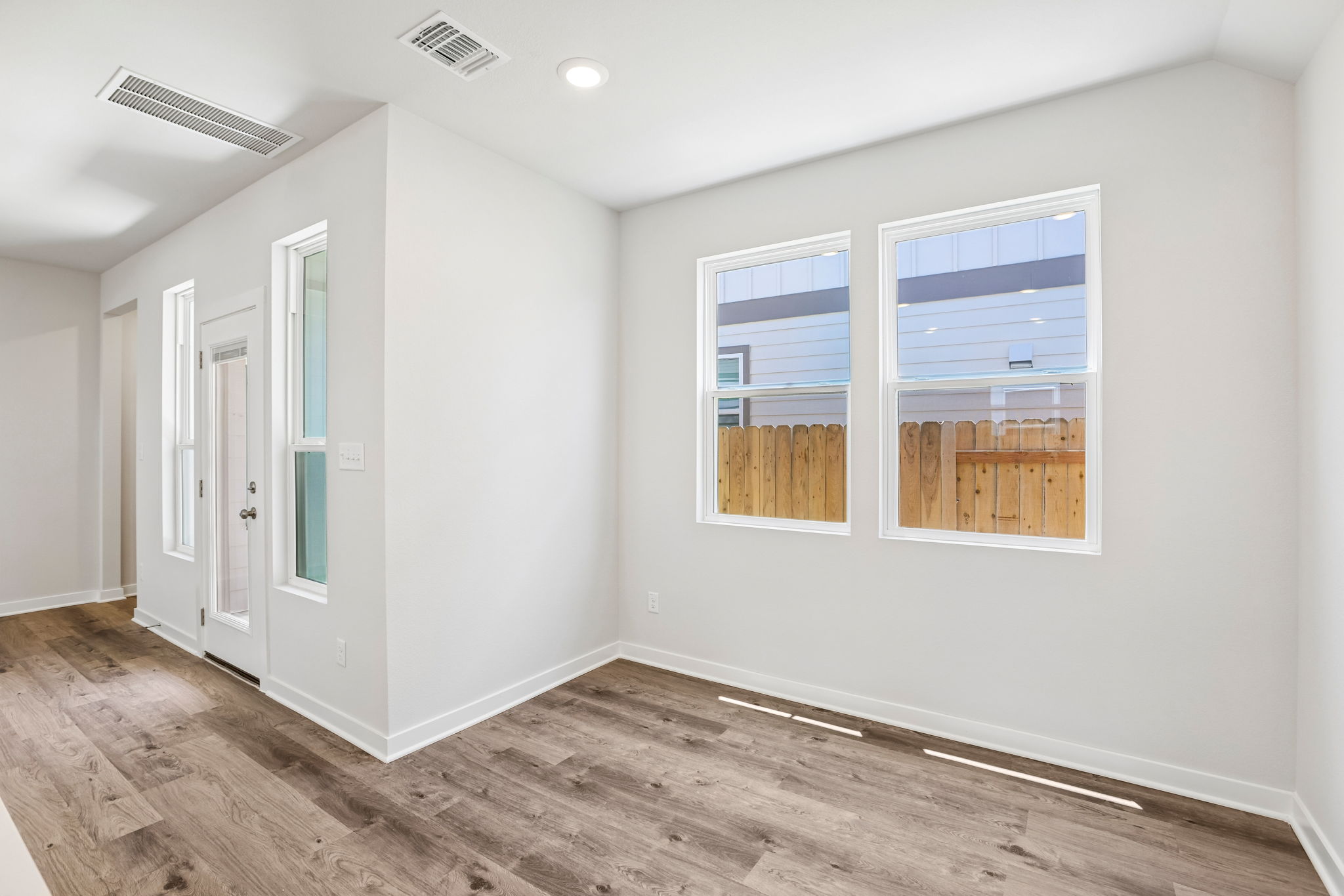 A room with a wood floor and a window with a view of the ocean.