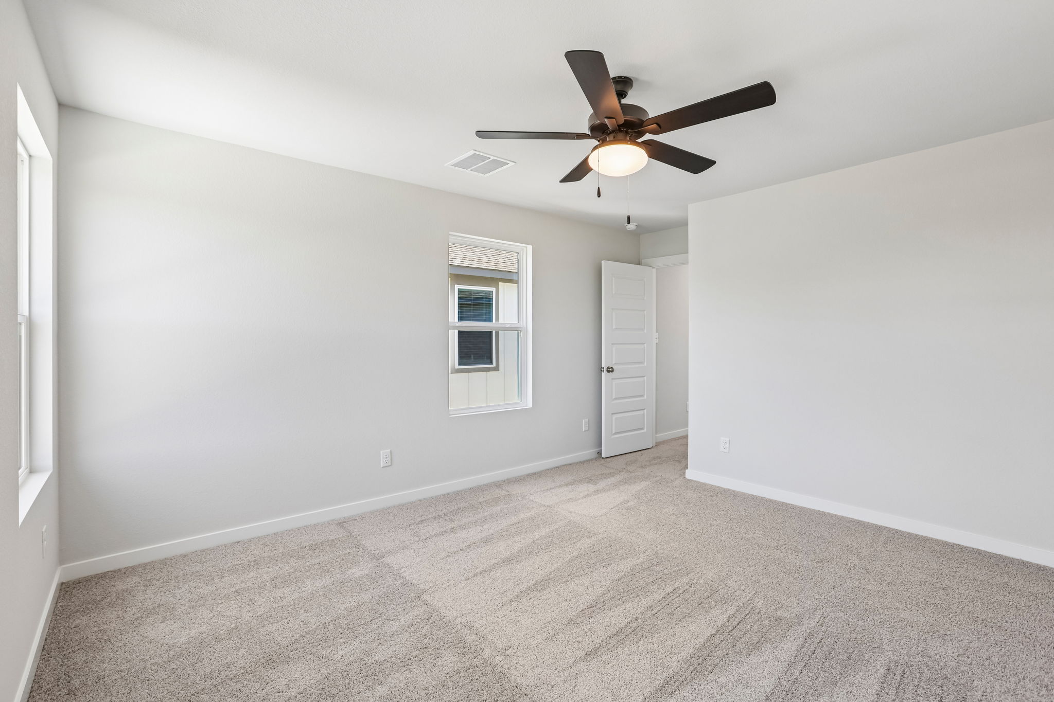 A room with a ceiling fan and a door.