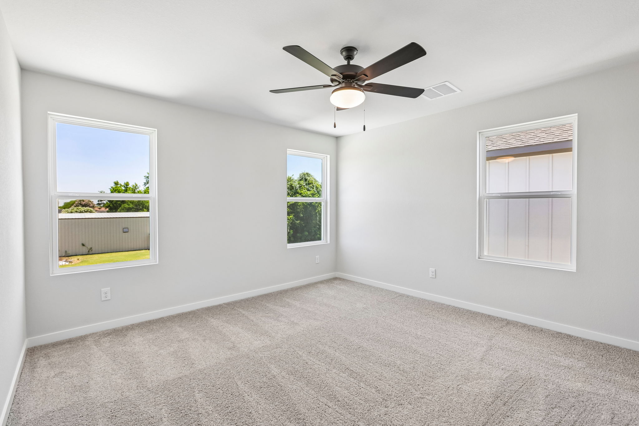 A room with a ceiling fan and windows.