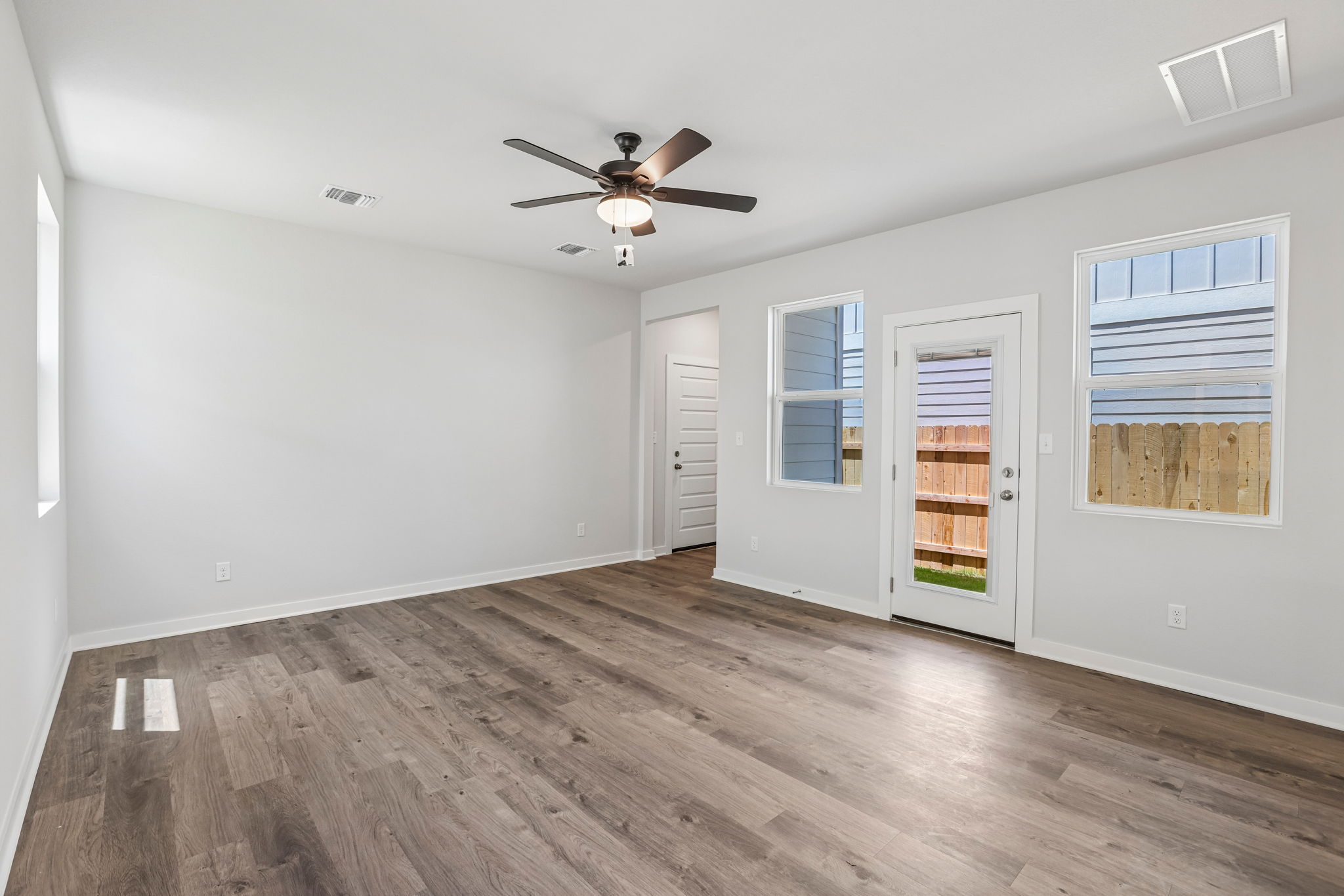 A room with a wood floor and a ceiling fan.