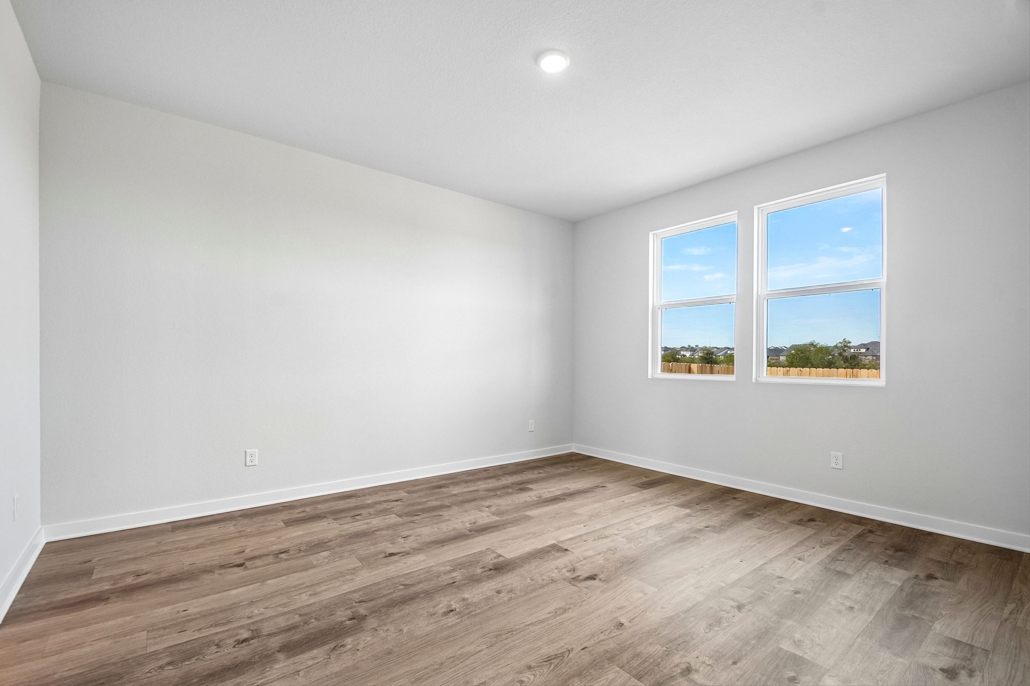 A room with a wood floor and a window with a view of the ocean.