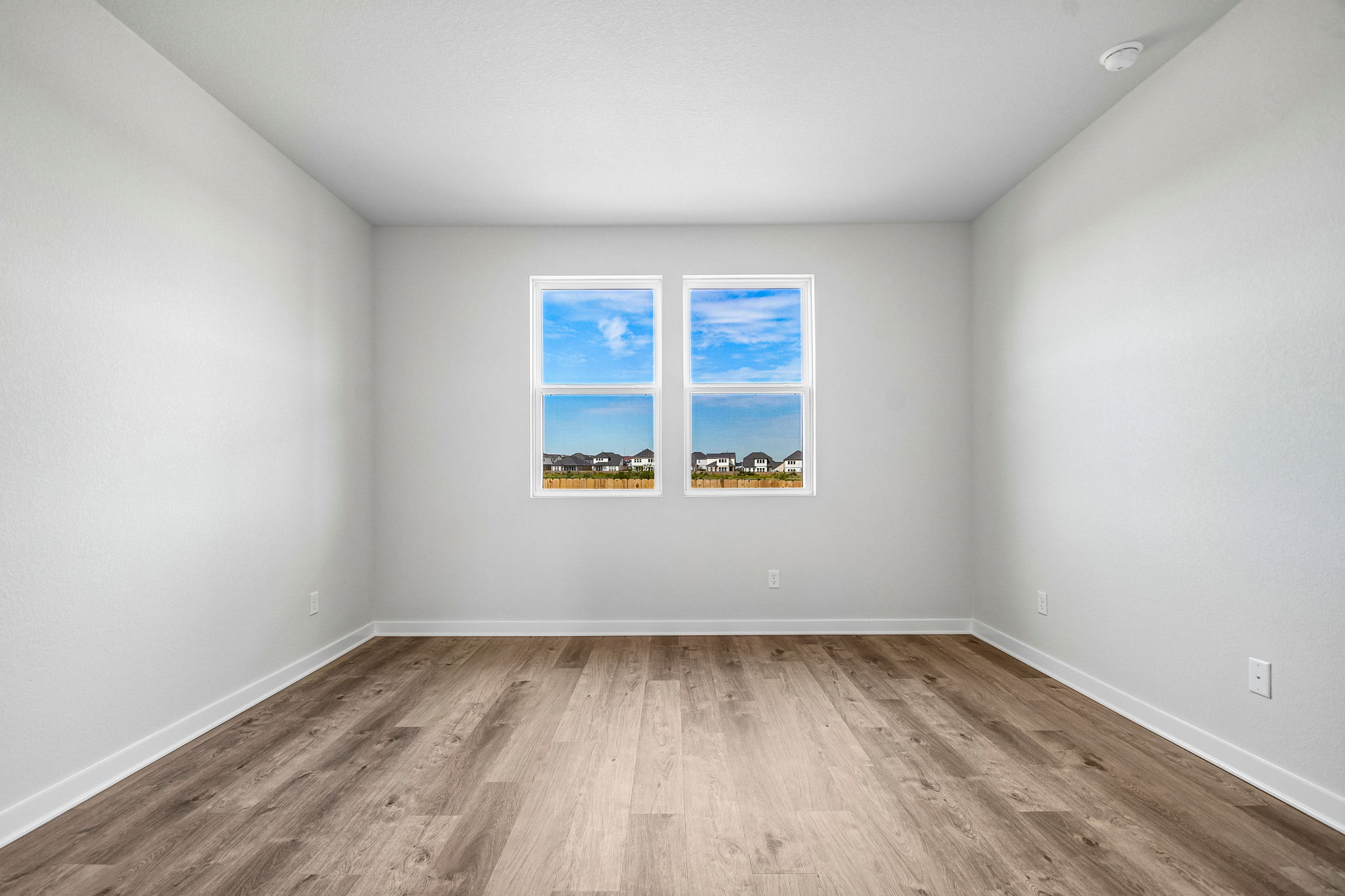 A room with a wood floor and a window with a painting on it.