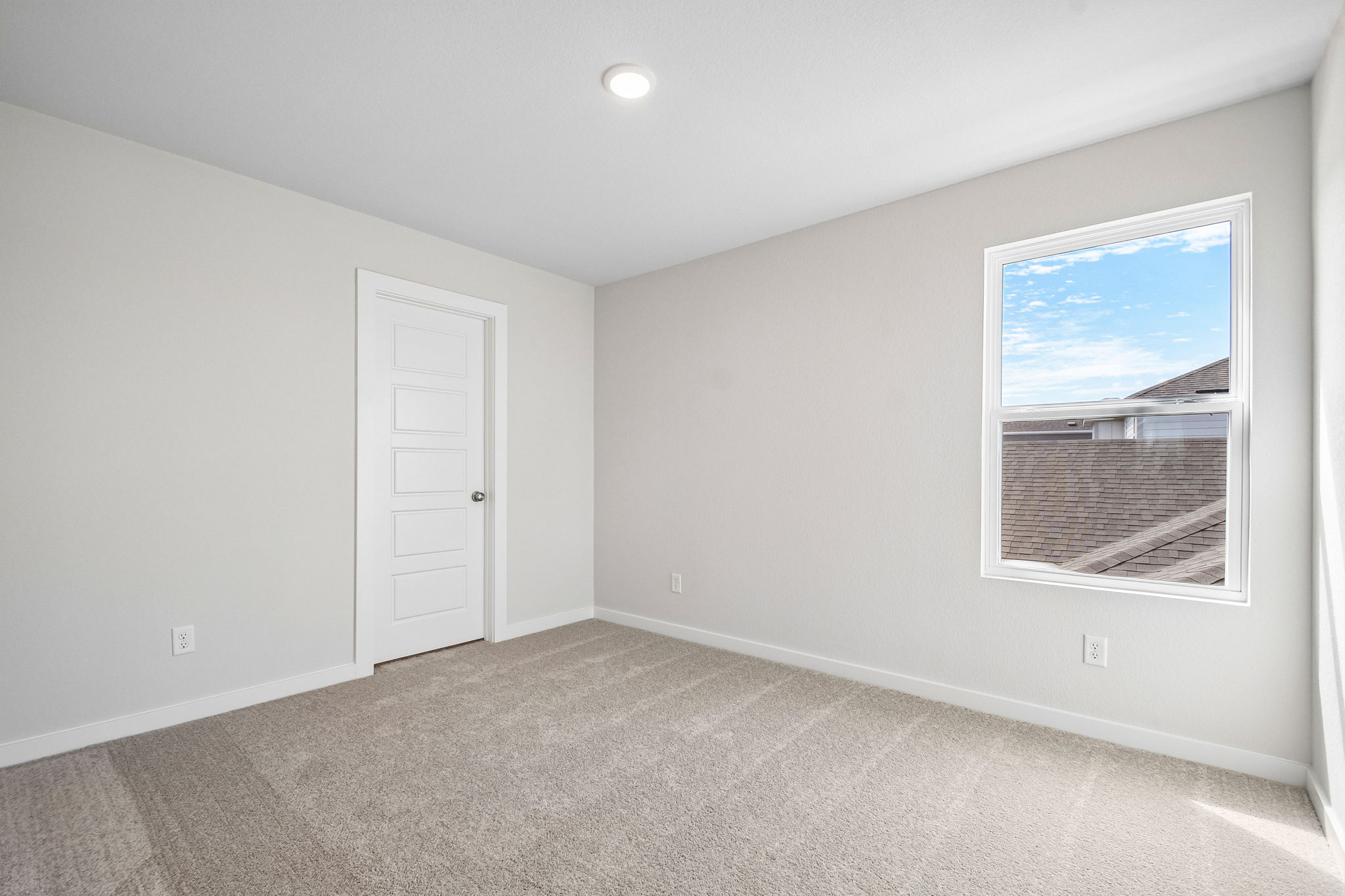 A room with a white door and a white wall with a painting on it.