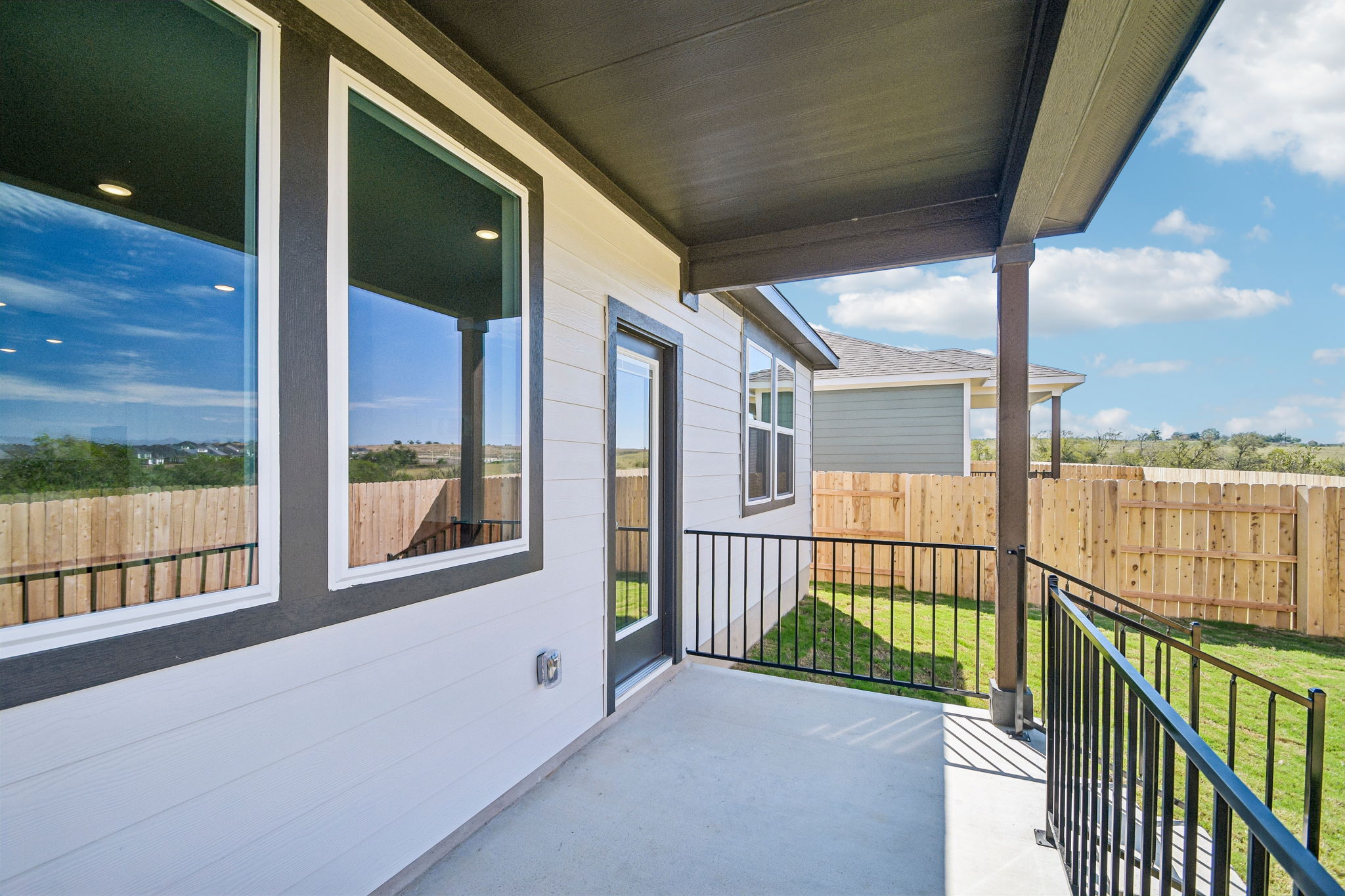 A deck with a fence and a house with a wood fence.