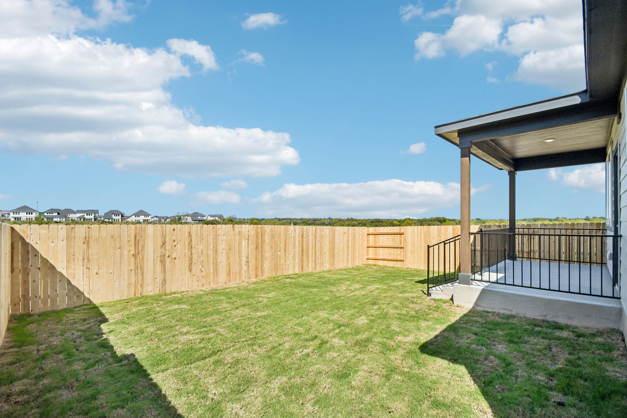 A fenced in yard with a wood fence and a building in the background.