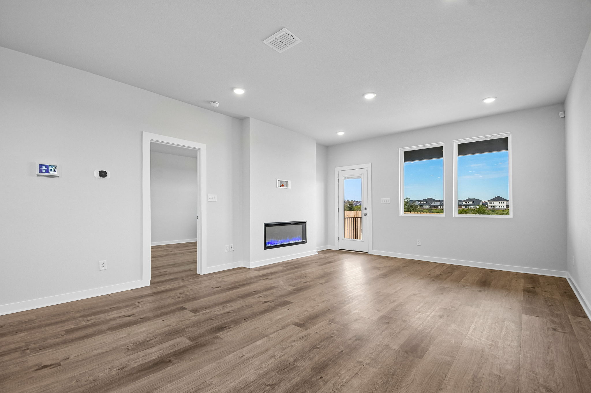 A room with a wood floor and a television on the wall.