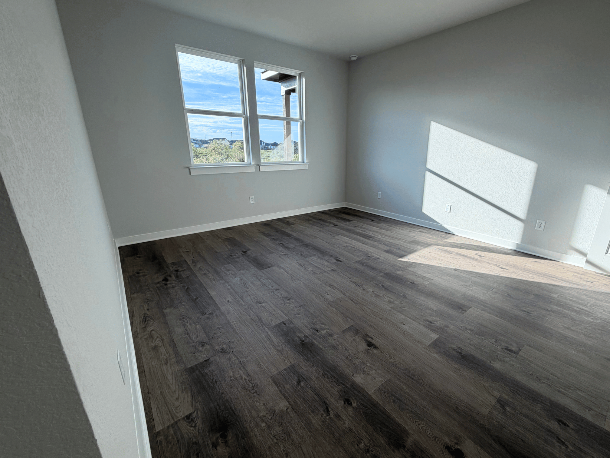 A room with a wood floor and a window.