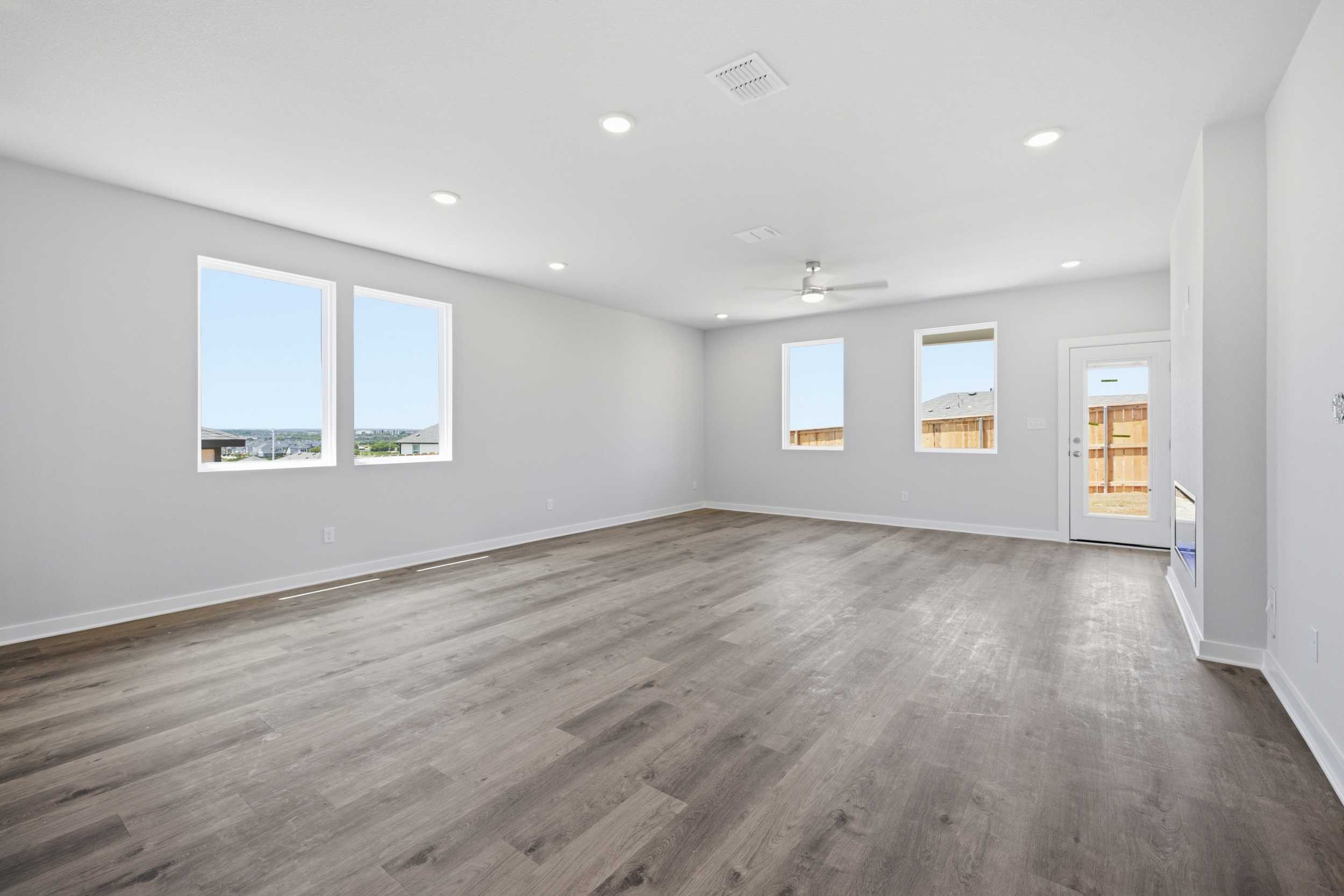 A room with a wood floor and a wood floor with a door and a window with a light.