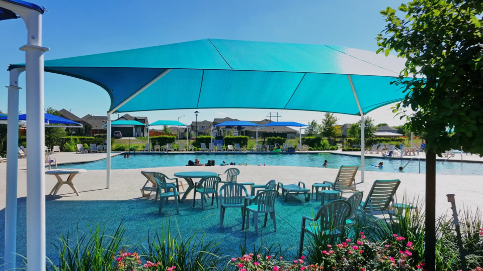 A pool with tables and chairs next to it.