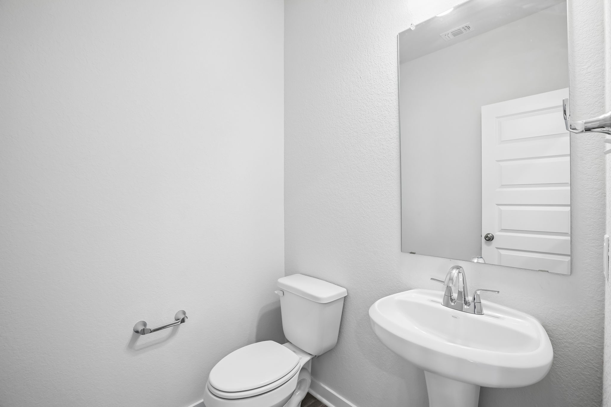 A bathroom with a sink toilet and mirror.