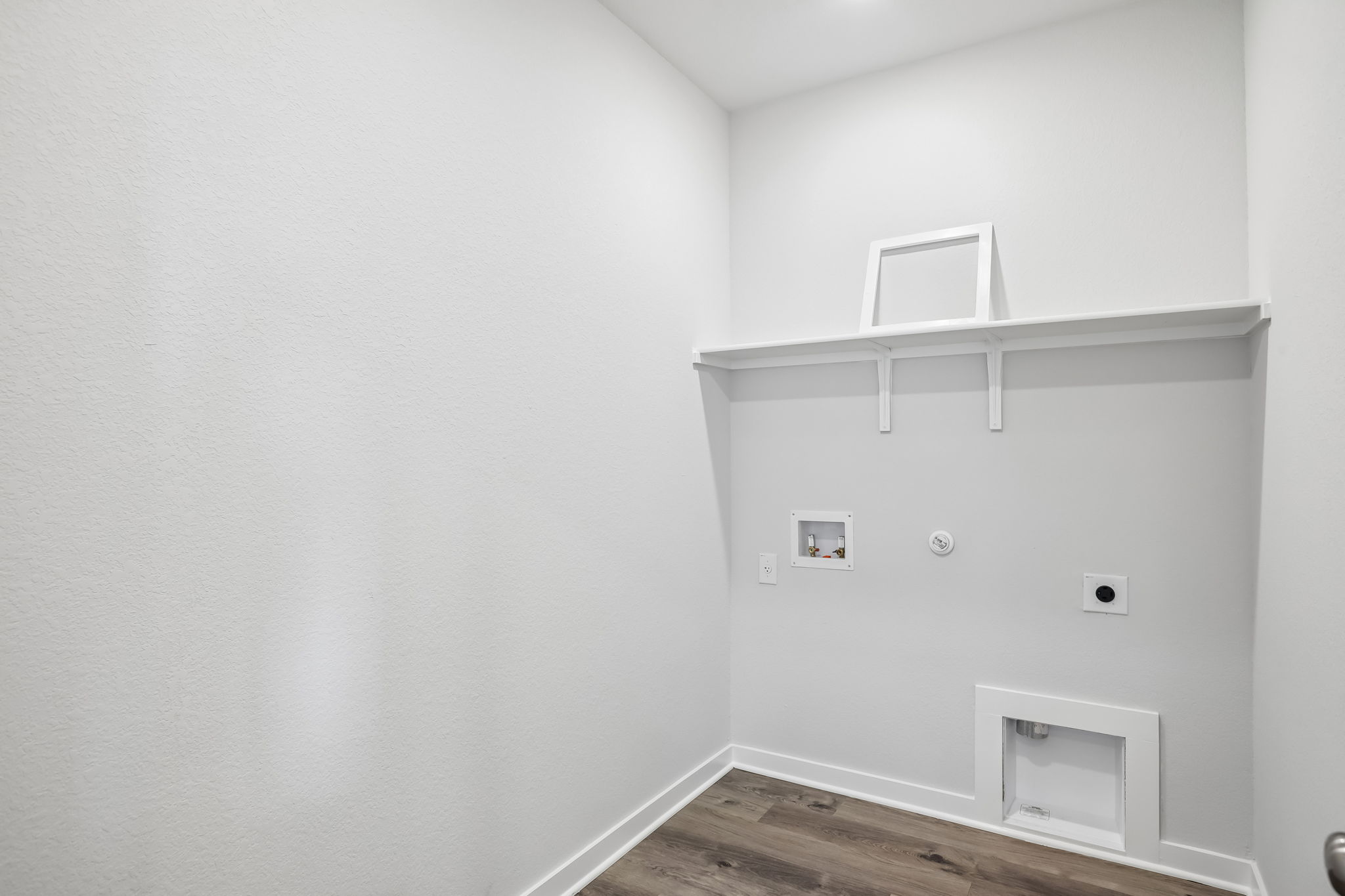 A white room with a shelf and a white wall.
