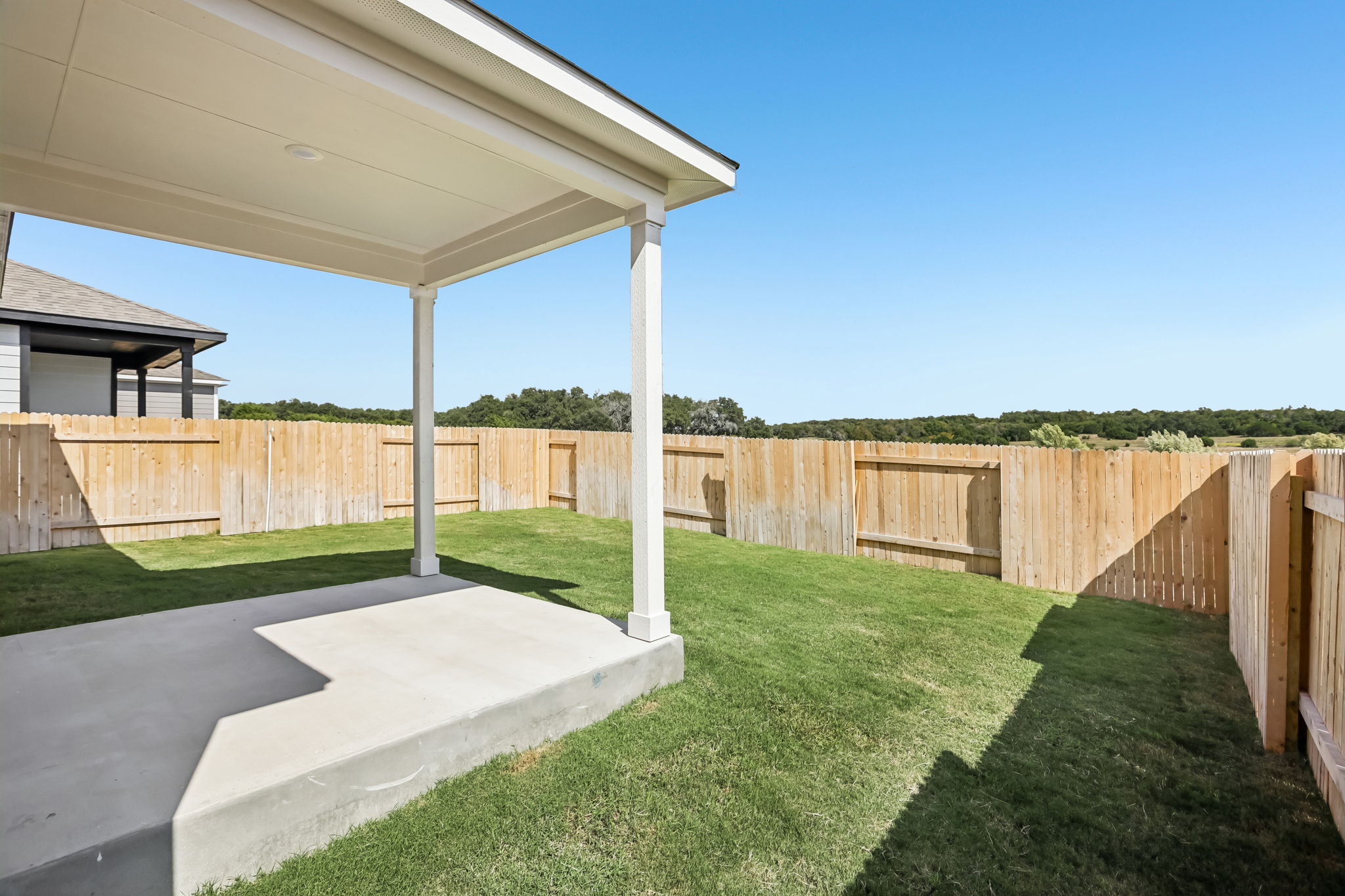 A fenced in yard with a covered patio and a covered patio.
