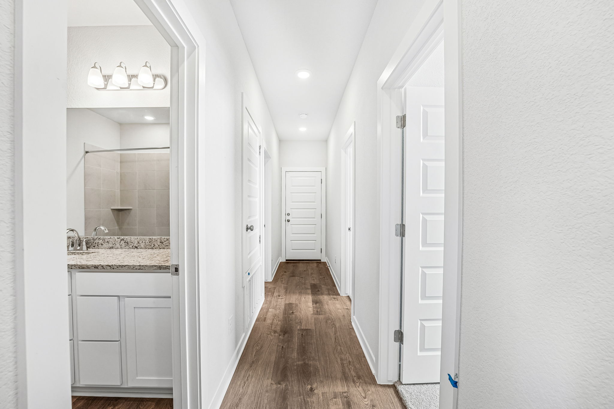 A hallway with white cabinets.