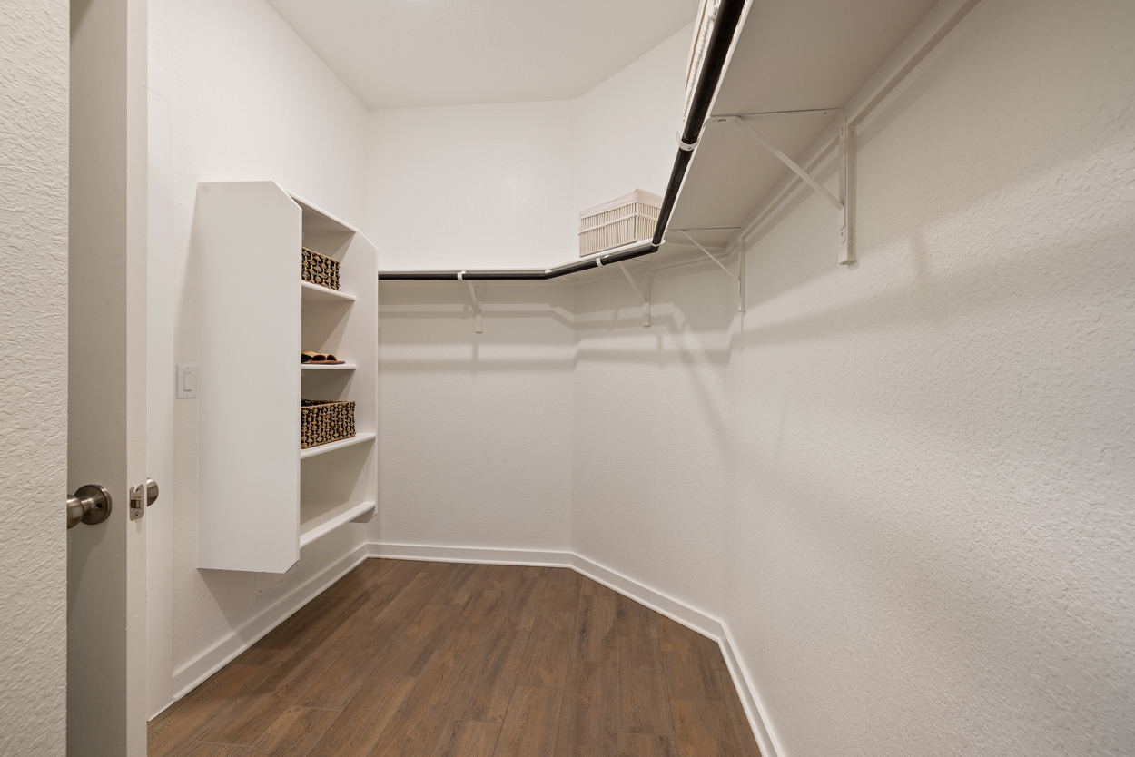 A room with a wood floor and a white wall with a white door.