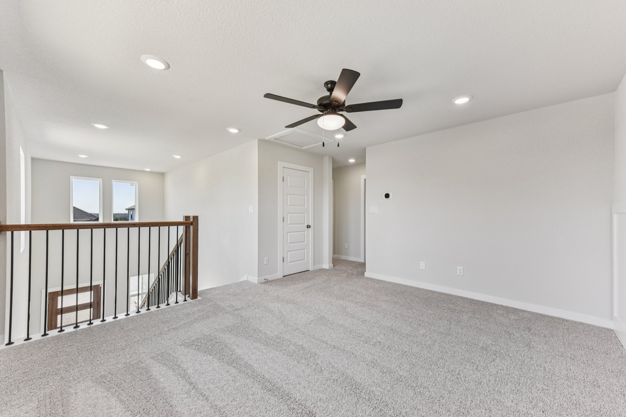 A room with a ceiling fan and a railing.