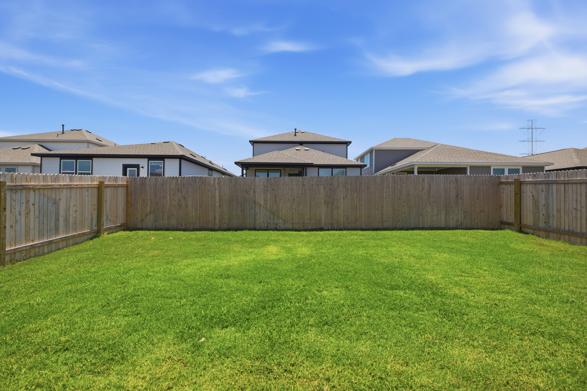 A fenced in yard with a house in the background.