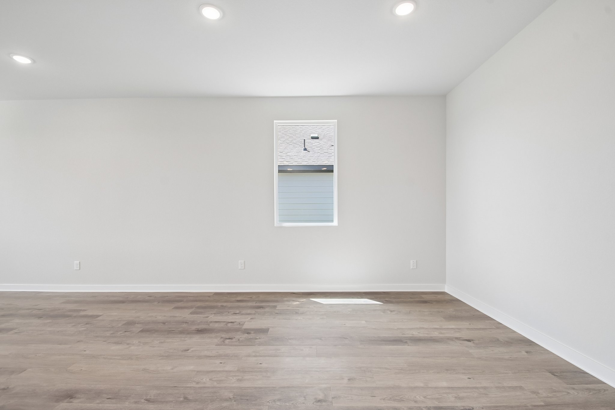 A room with a wood floor and a white wall with a sign on it.
