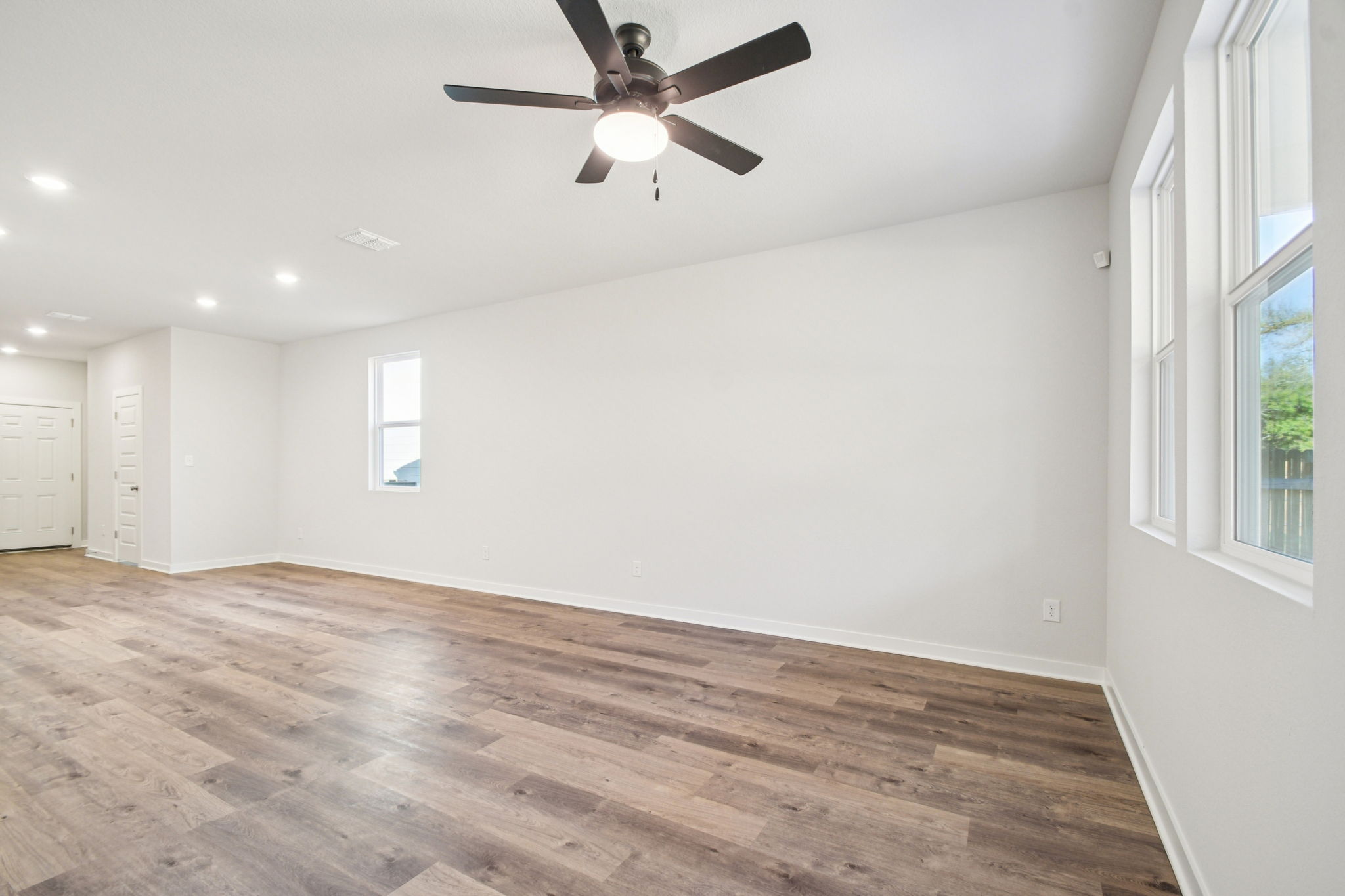 A room with a ceiling fan and a wood floor.