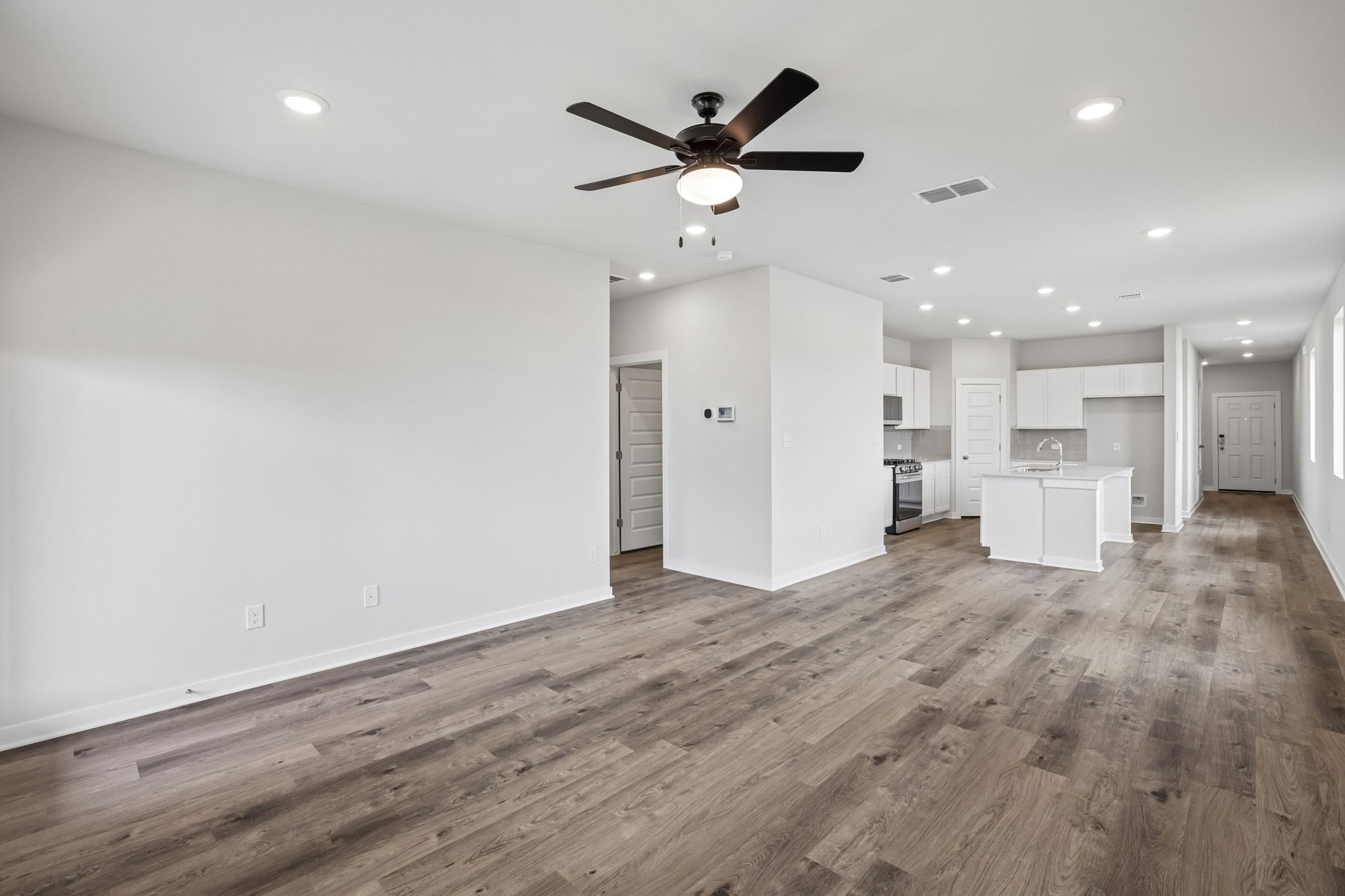 A large empty room with a wood floor and a ceiling fan.