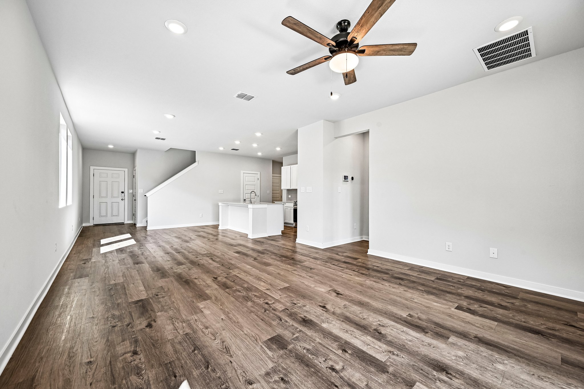 A large empty room with a wood floor and a ceiling fan.