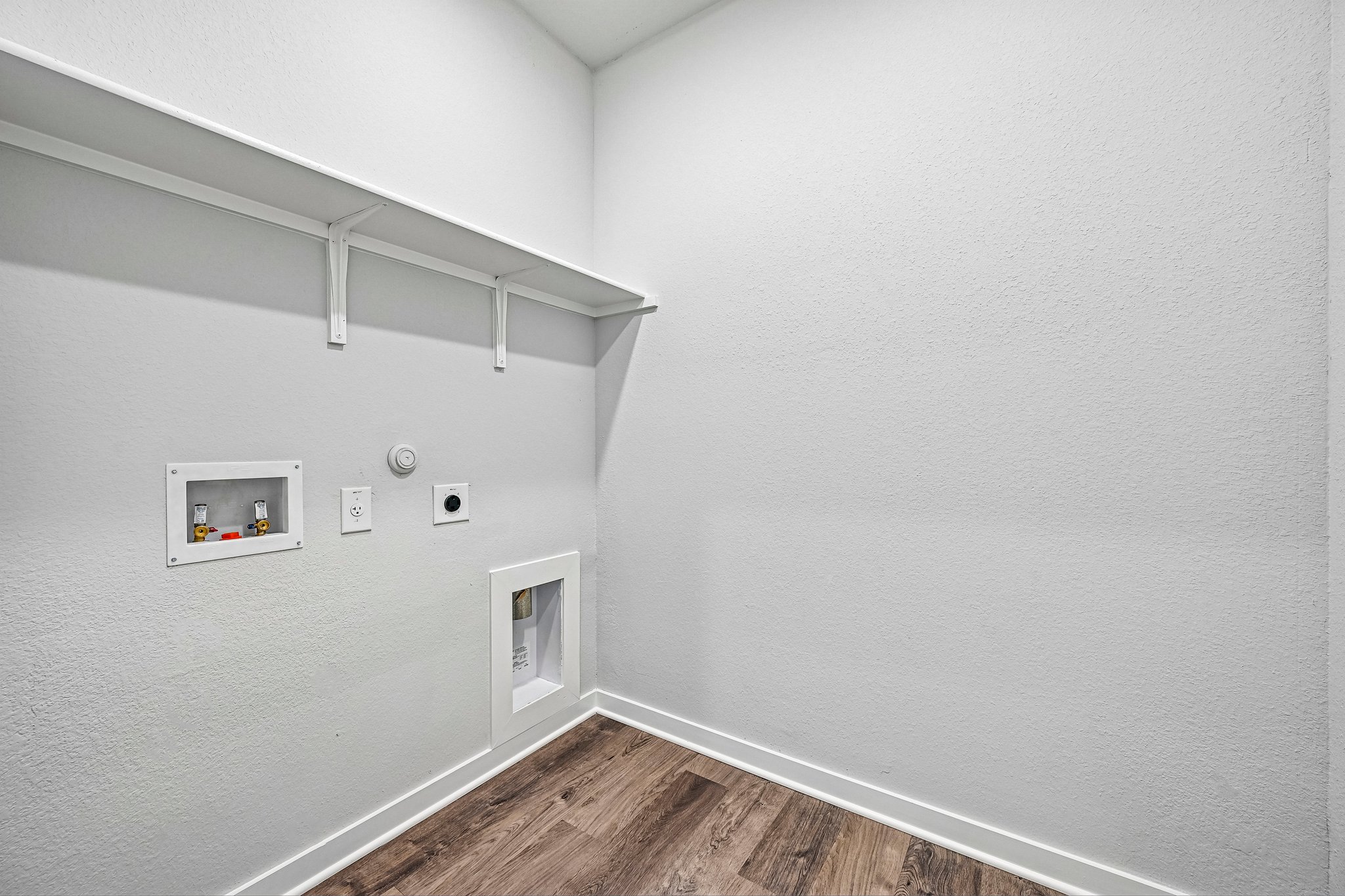 A white room with a wood floor and a white wall with a white ceiling and a wood floor.