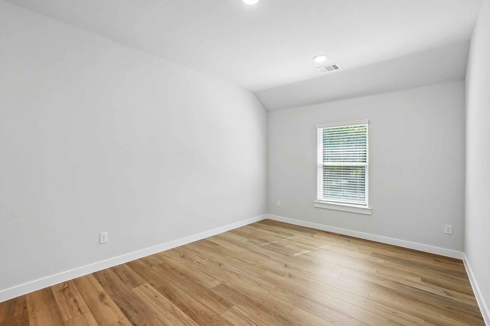 A room with a wood floor and a window.