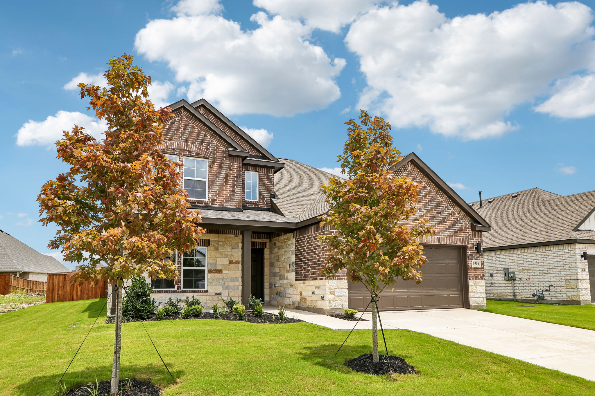 A brick house with a tree in the front yard.