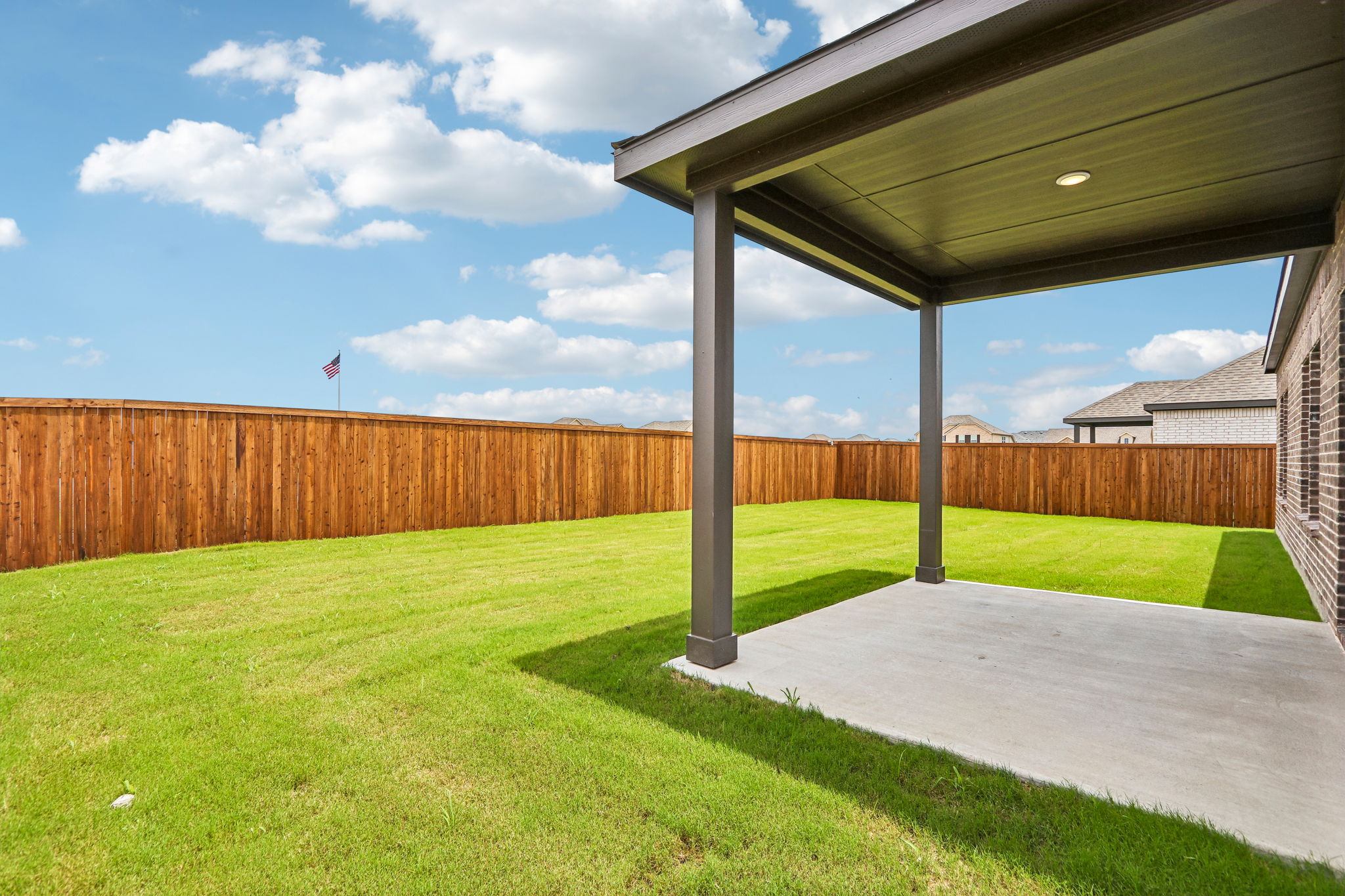 A backyard with a fence and a grass yard.