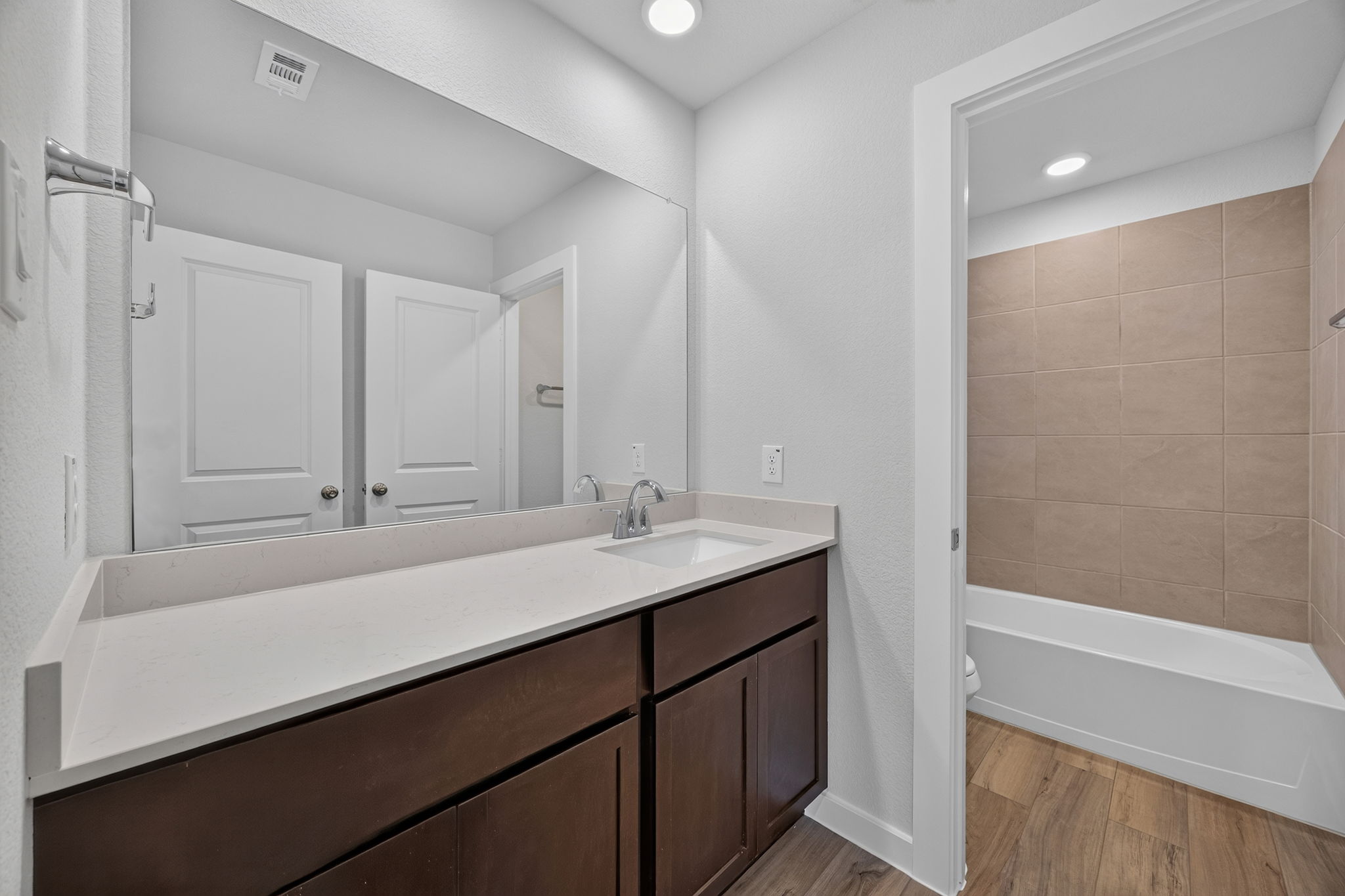 A bathroom with a tub sink and a mirror.