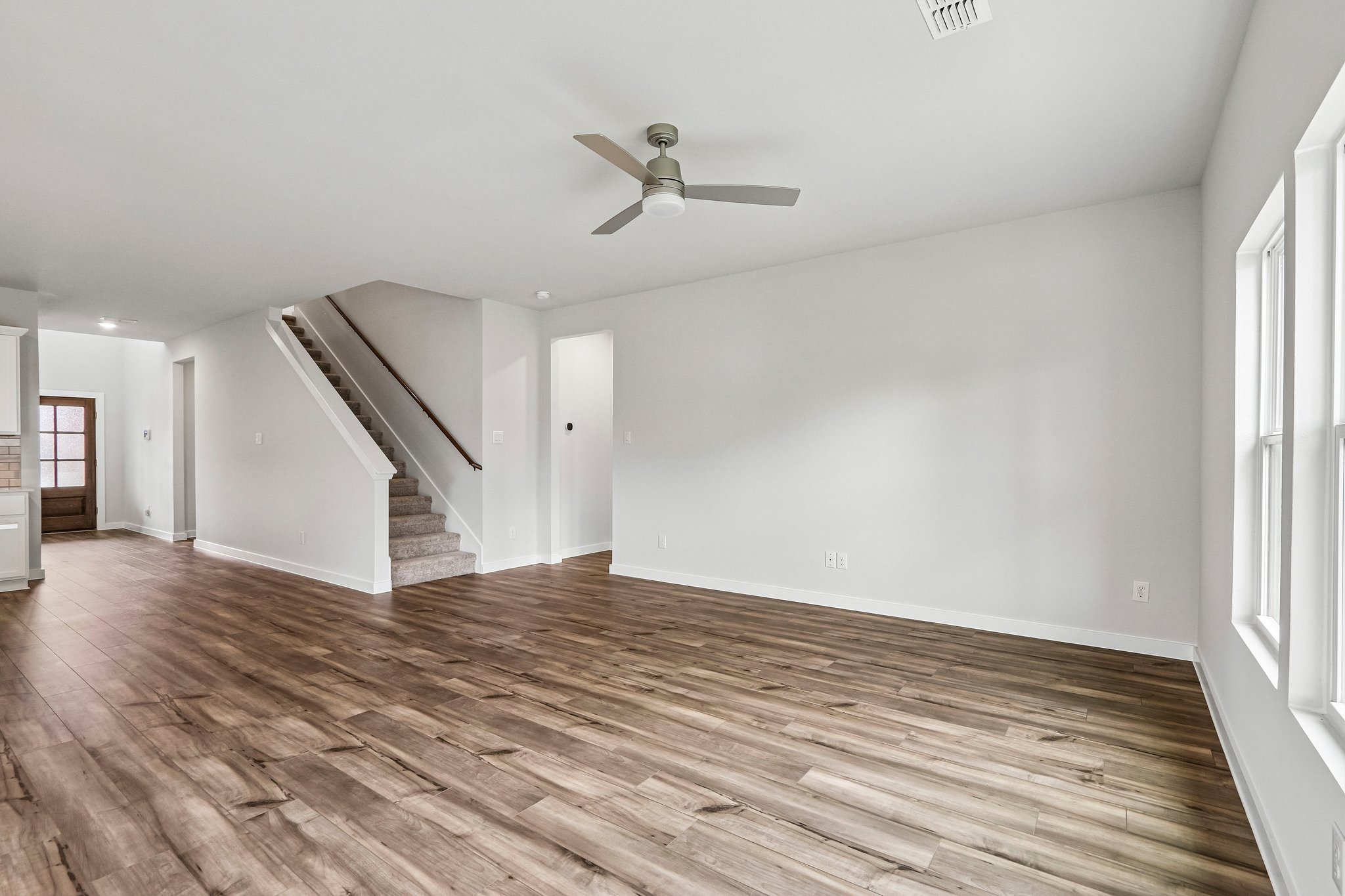 A room with a wood floor and a wood floor with a ceiling fan.