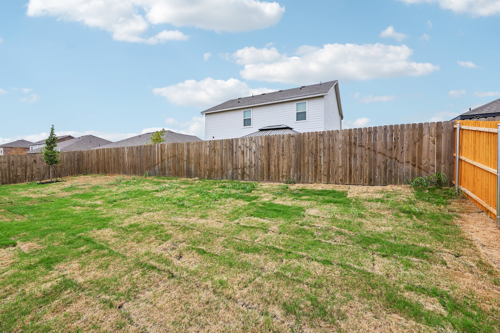 A fenced in yard with a house in the background.