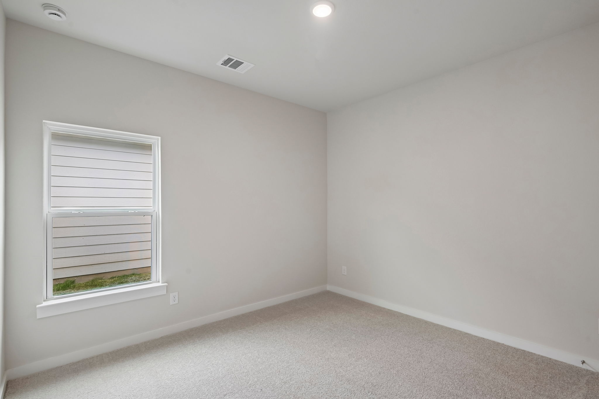 A room with a window and a white wall.