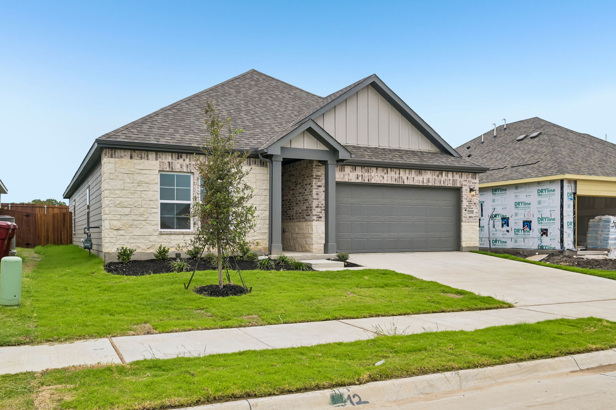 A house with garages and a tree in the front.
