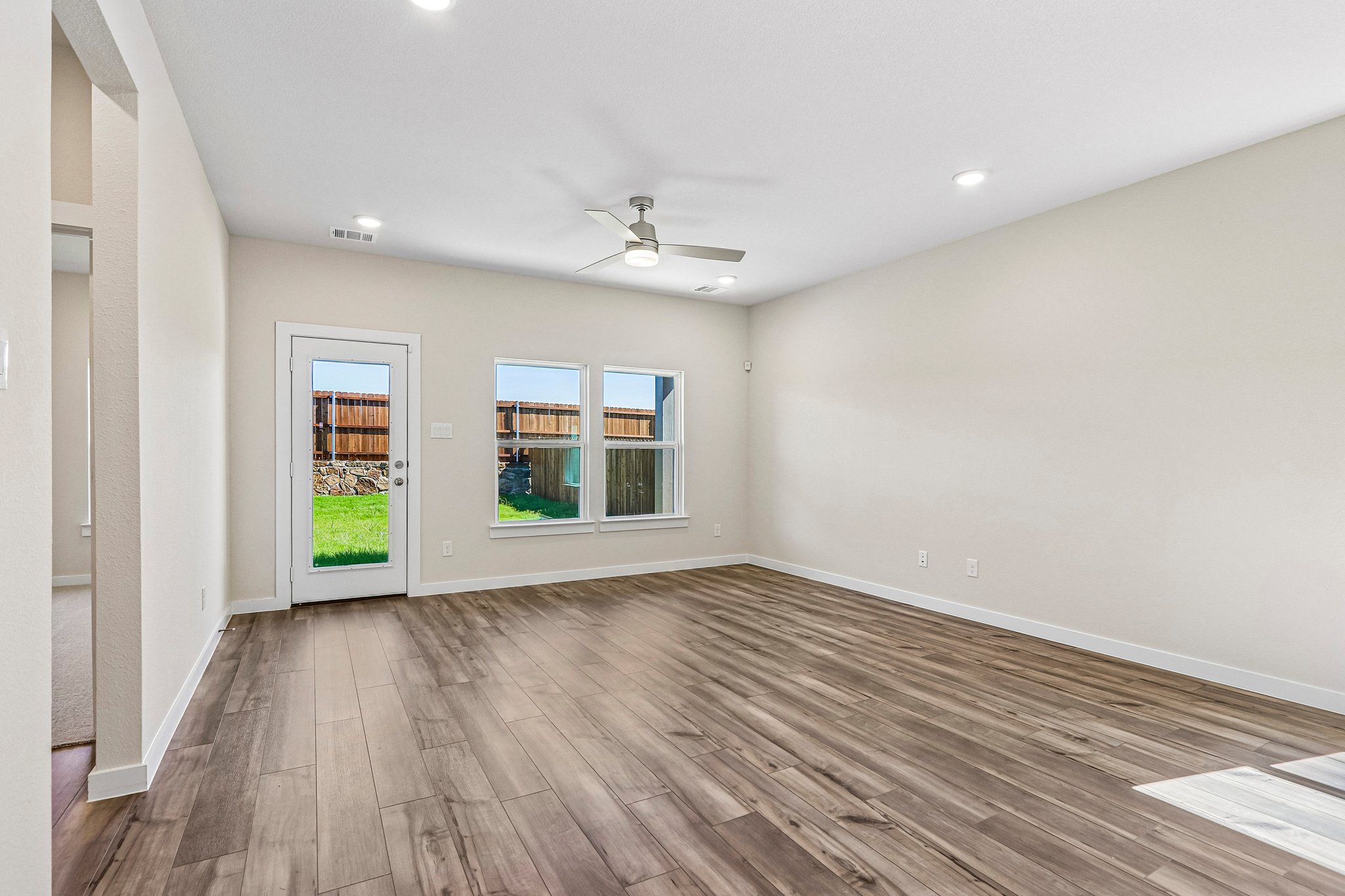 A room with a wood floor and a wood floor with a ceiling fan.